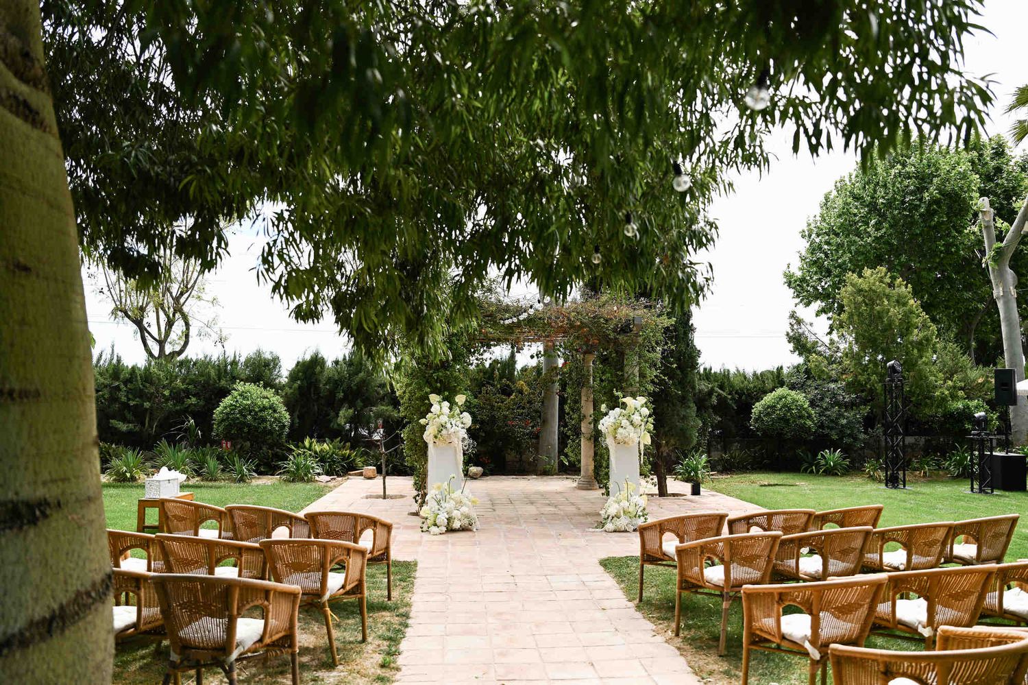 Outdoor wedding ceremony setup with wooden chairs and beautiful white floral pillars on the lawn at Villa Paula.