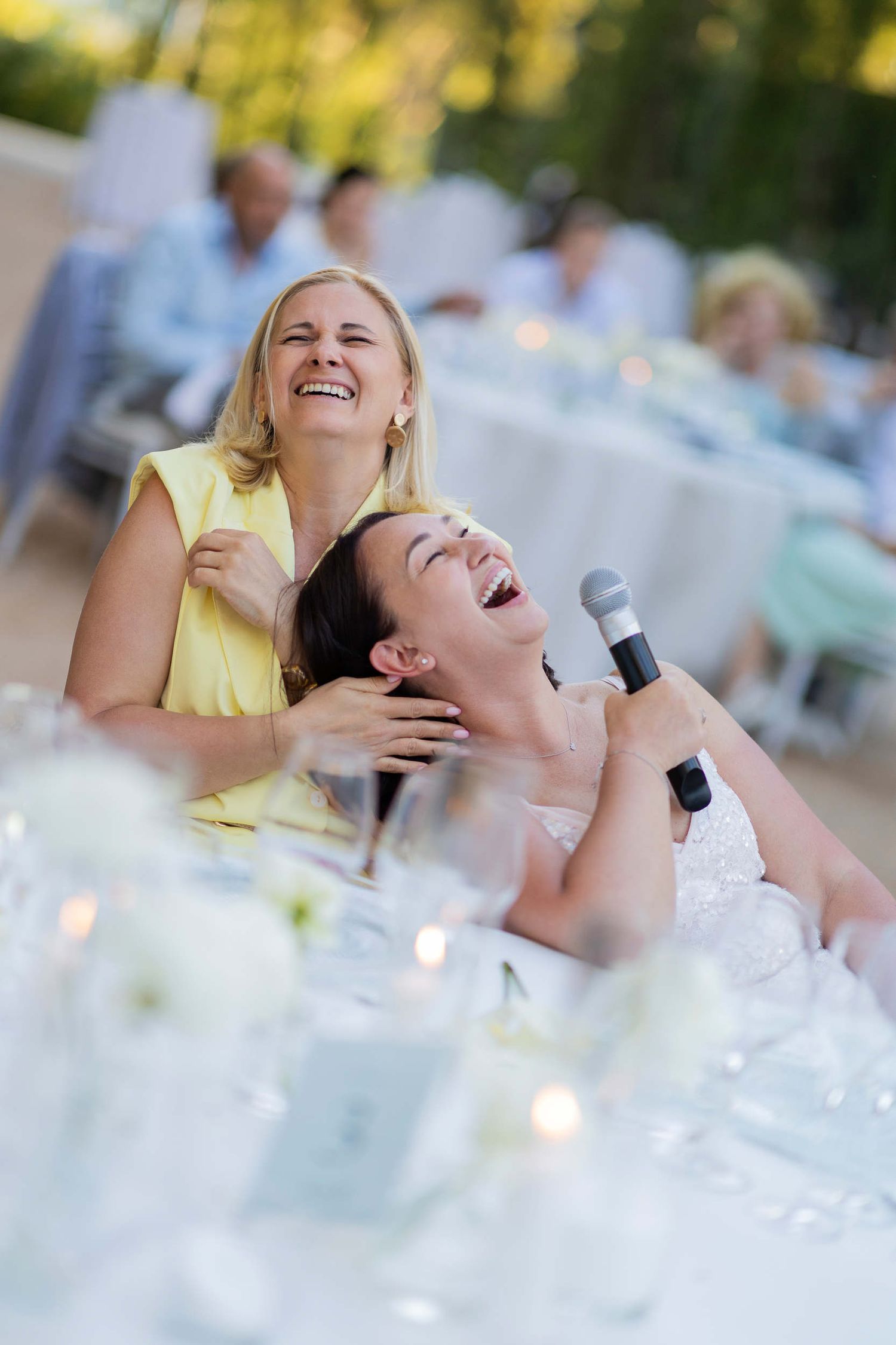 Joyful bride and guests laughing out loud during a funny wedding speech in Altea