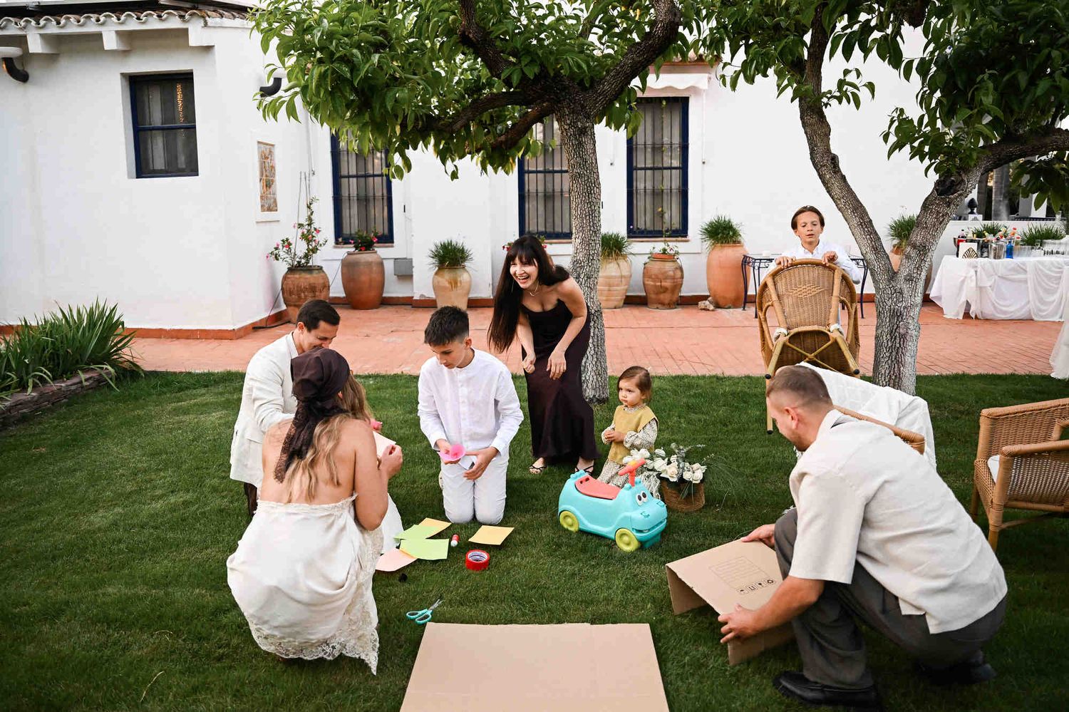 Guests playing a fun team game building a cardboard dream house on the grass at a Valencia wedding reception.
