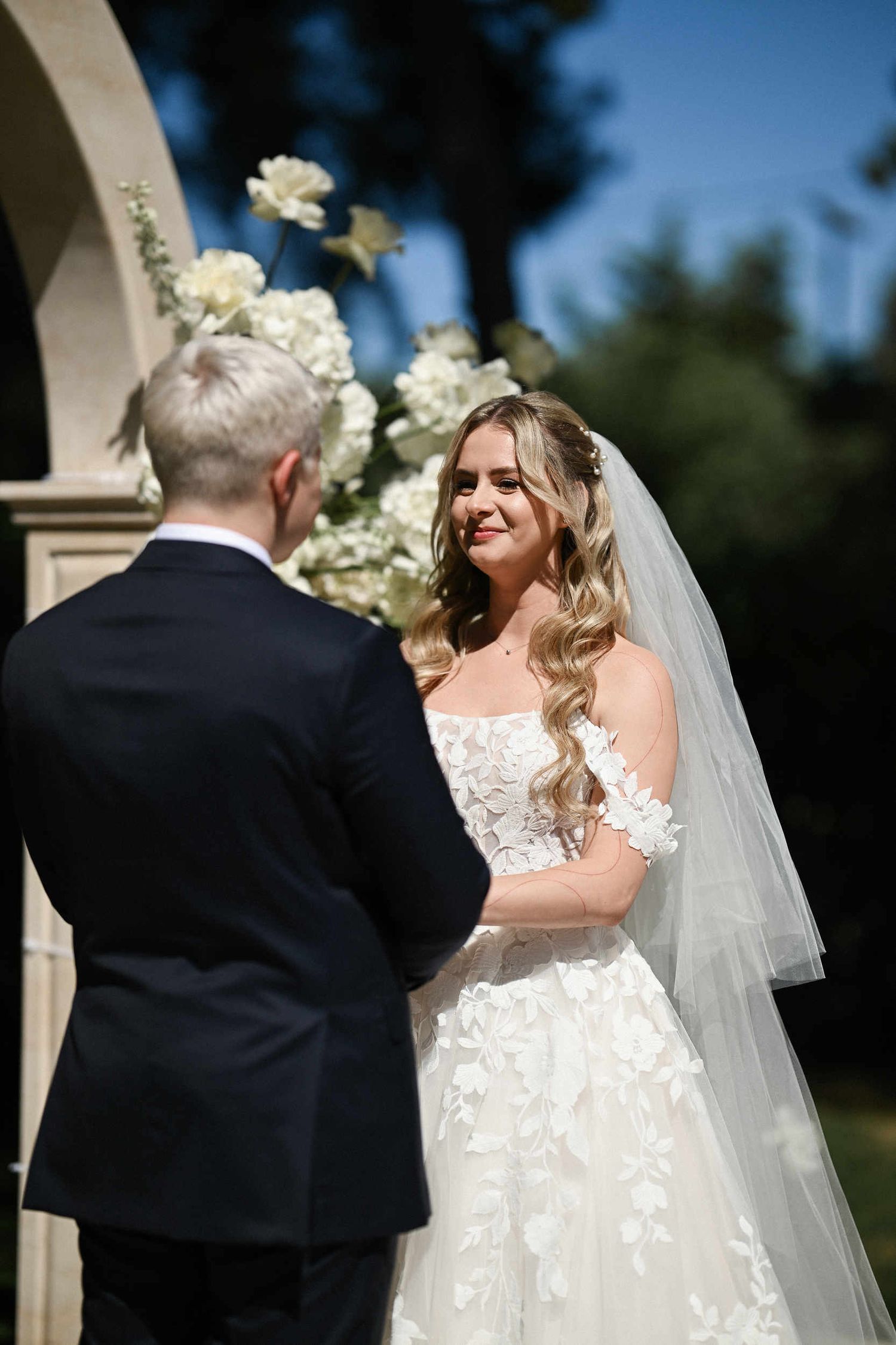 Smiling bride holding hands with the groom during their emotional outdoor wedding ceremony at Finca El Senyoret in Spain.