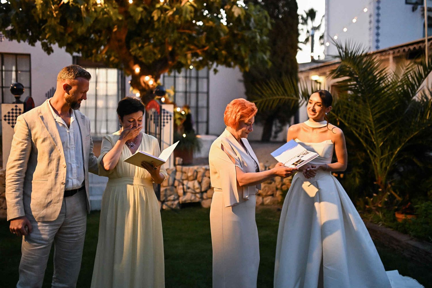 Bride and groom presenting childhood photo albums to their mothers during a touching sunset wedding moment at Villa Paula