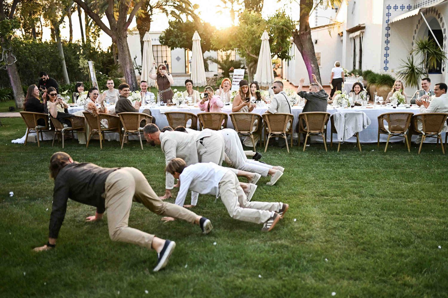Wedding guests and groom having fun playing active games on the grass during an outdoor reception in Valencia.