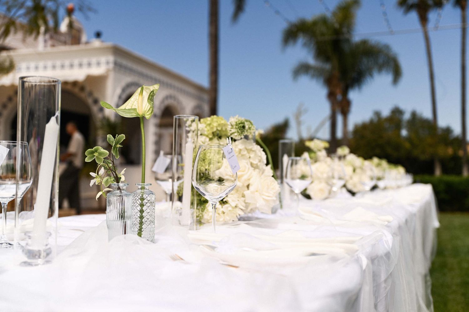 Elegant outdoor wedding table setting with white florals and candles against the historic facade of Villa Paula near Valencia.