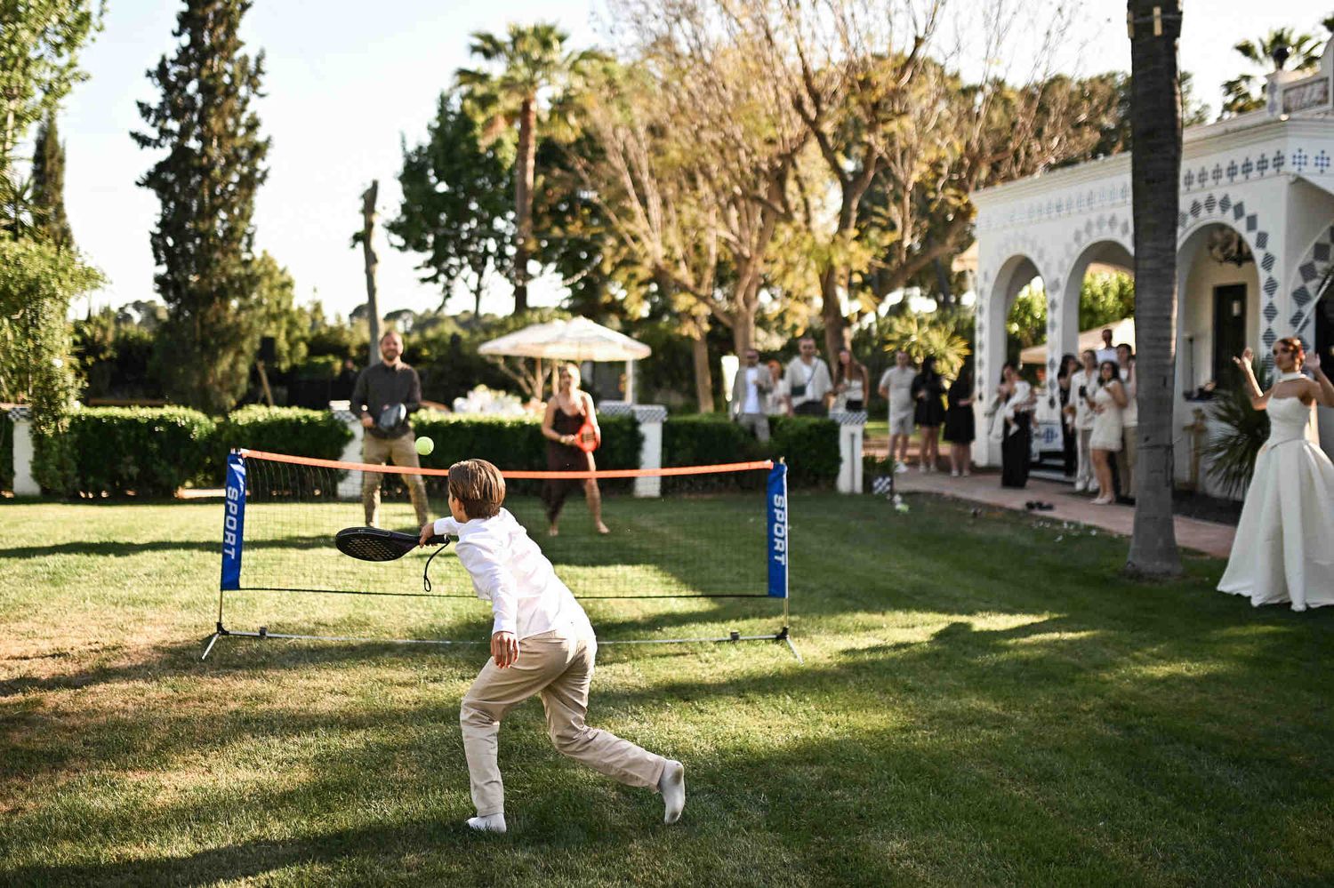 Young boy playing padel on the lawn during a fun outdoor wedding reception at Villa Paula