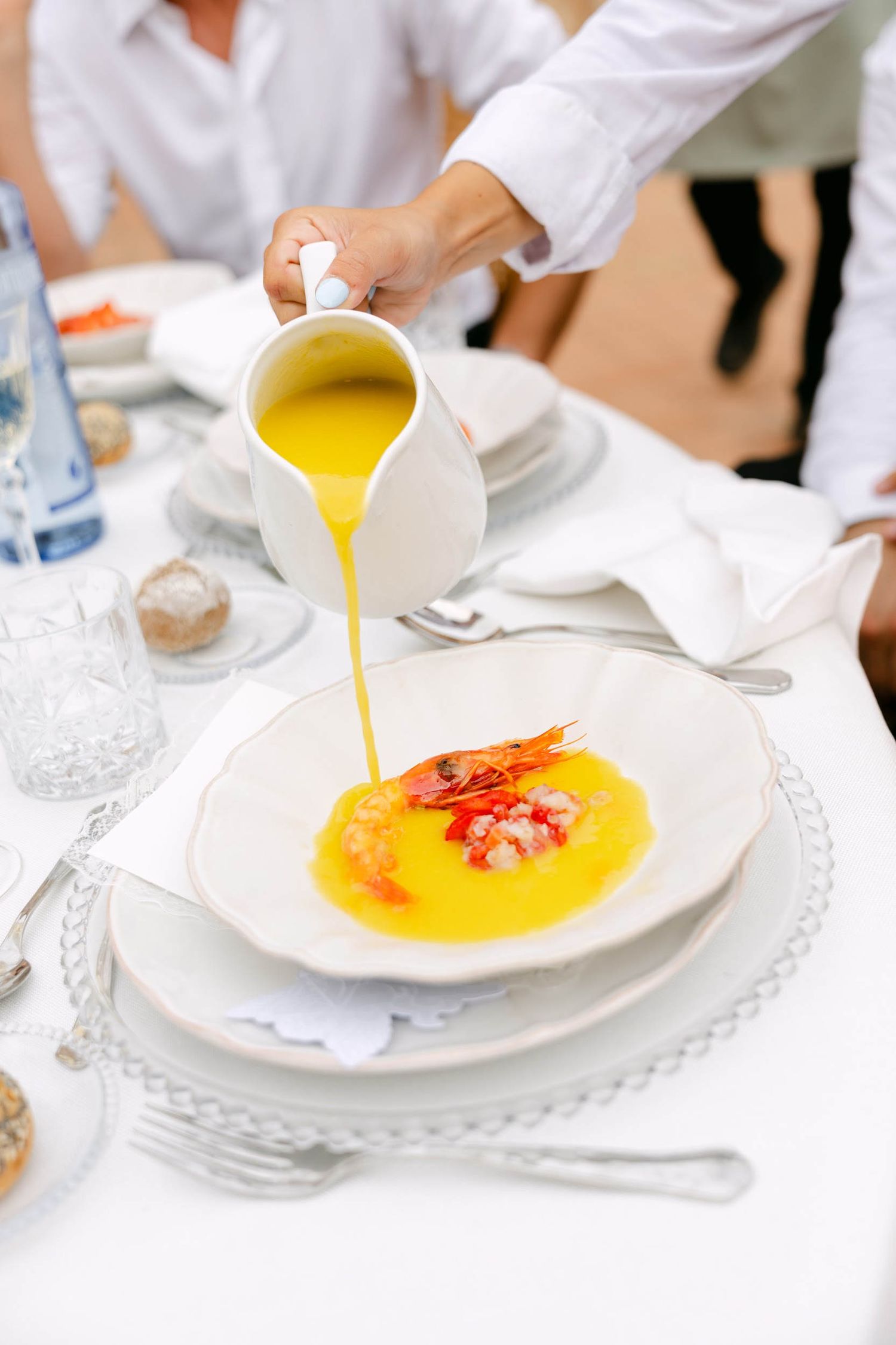 Waiter pouring yellow sauce over a plated red prawn dish during a fine dining wedding reception meal at La Cartuja monastery.