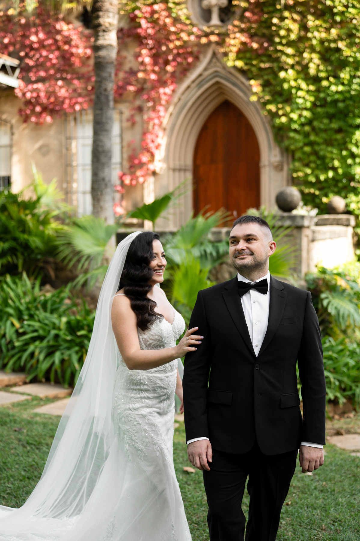 Bride touching the groom’s shoulder for their first look by the ivy-covered chapel at Casa Santonja.