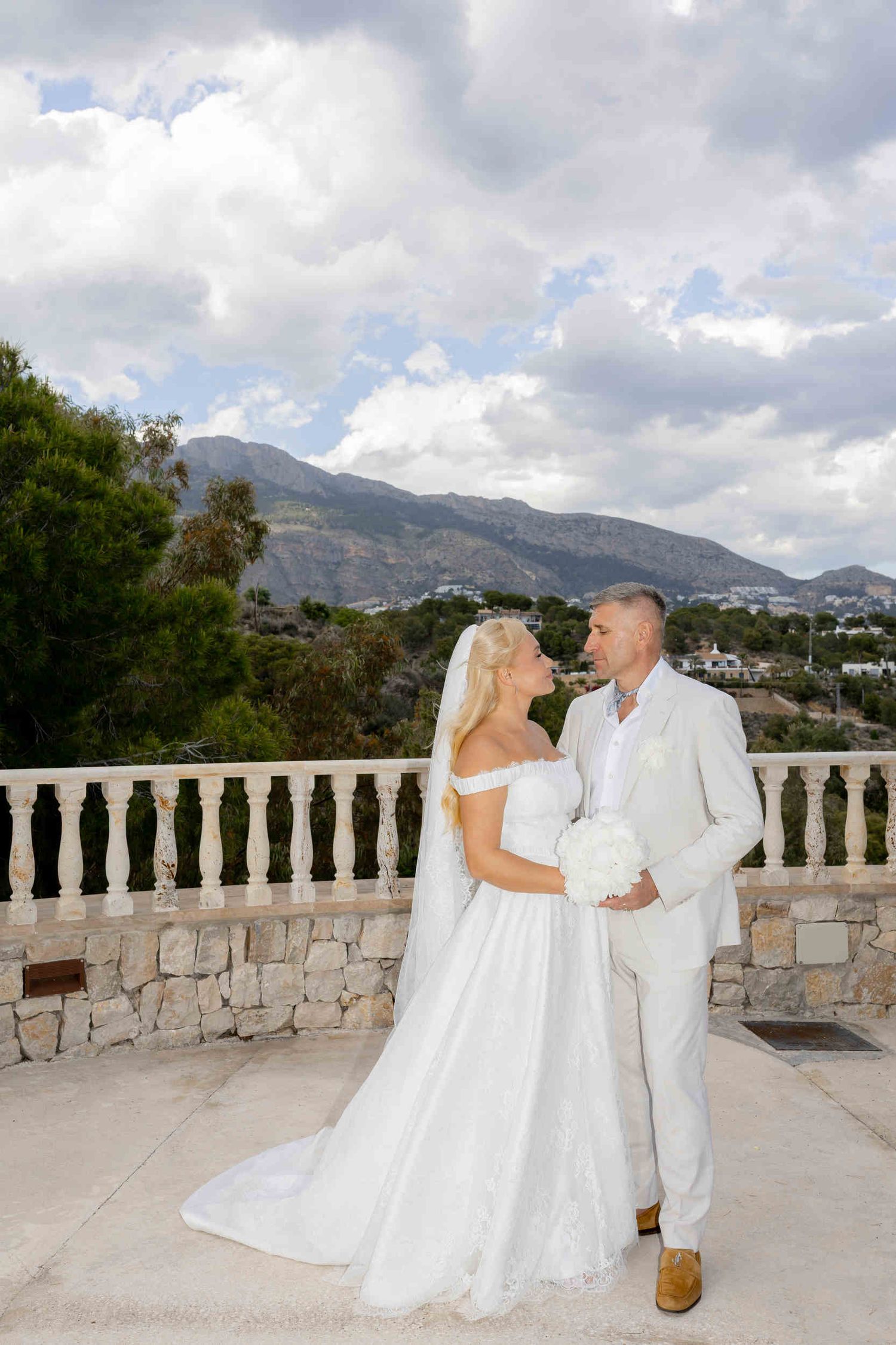 Bride and groom looking at each other on a scenic terrace with stunning mountain views during their destination wedding in Altea.