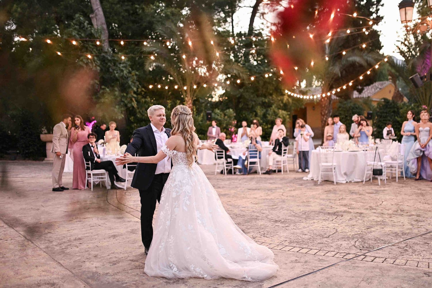 Newlyweds sharing a romantic first dance under string lights during an outdoor evening wedding reception in Valencia.