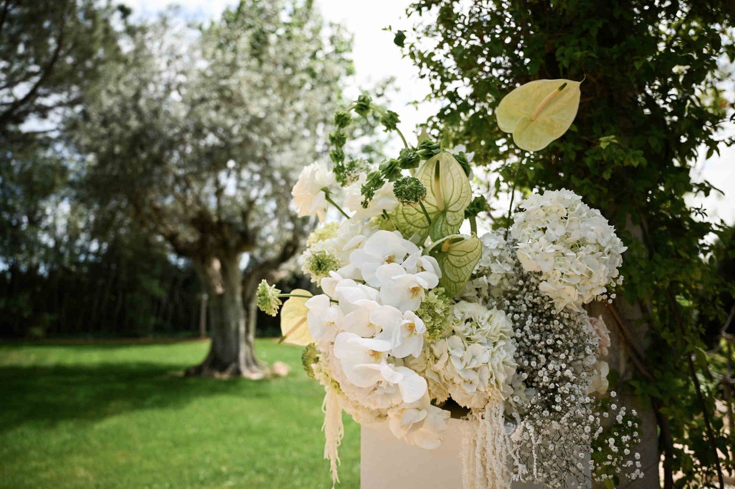 Elegant white wedding floral arrangement with orchids and hydrangeas in the gardens of Villa Paula