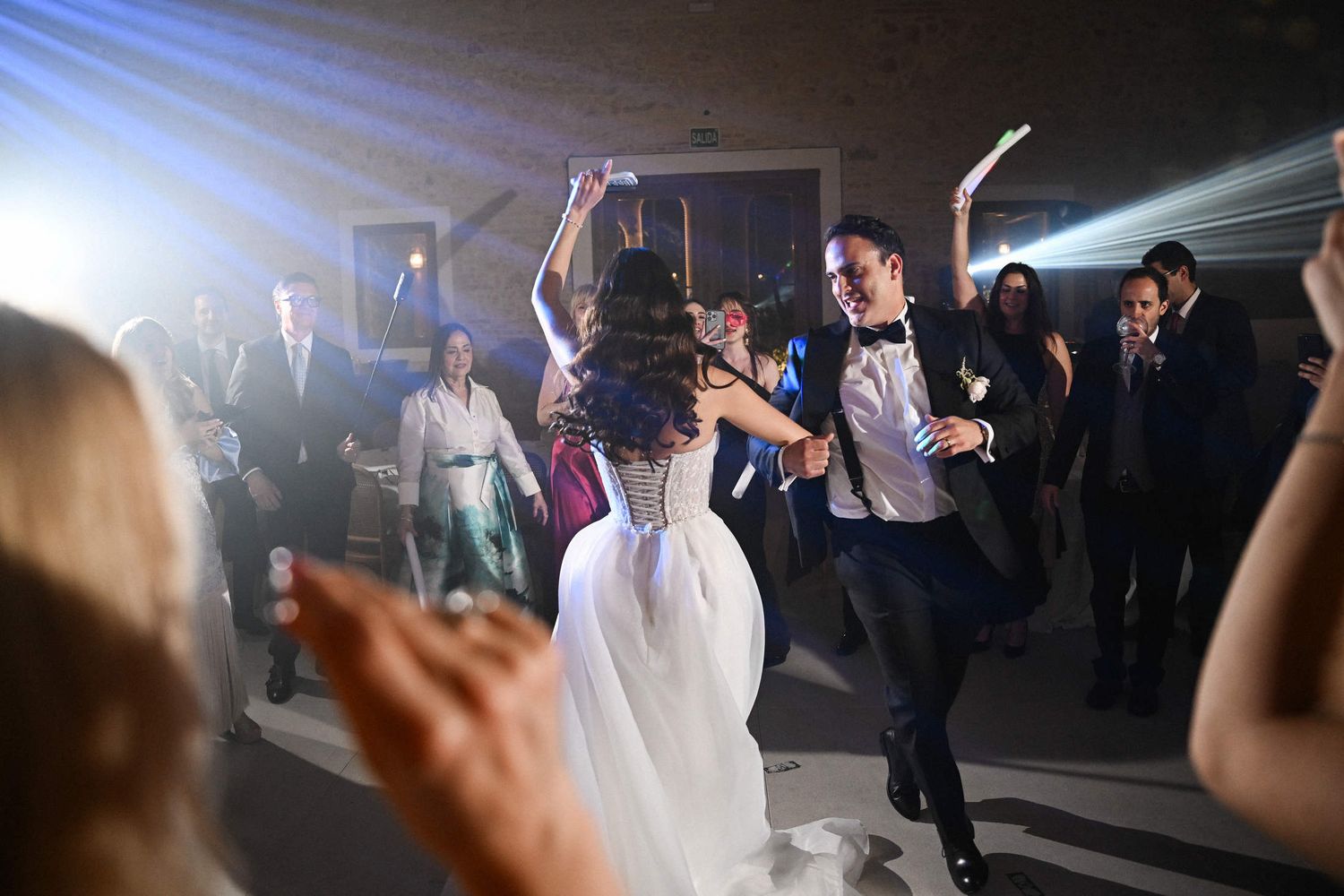 Bride and groom dancing with glow sticks on the dance floor surrounded by guests at their Valencia wedding party.