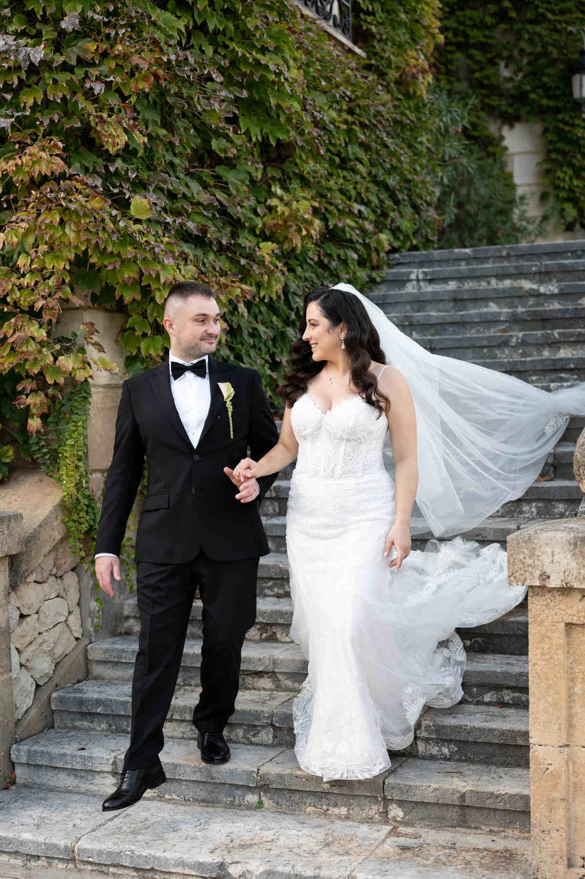 Bride and groom walking down stone stairs past an ivy-covered wall at Casa Santonja
