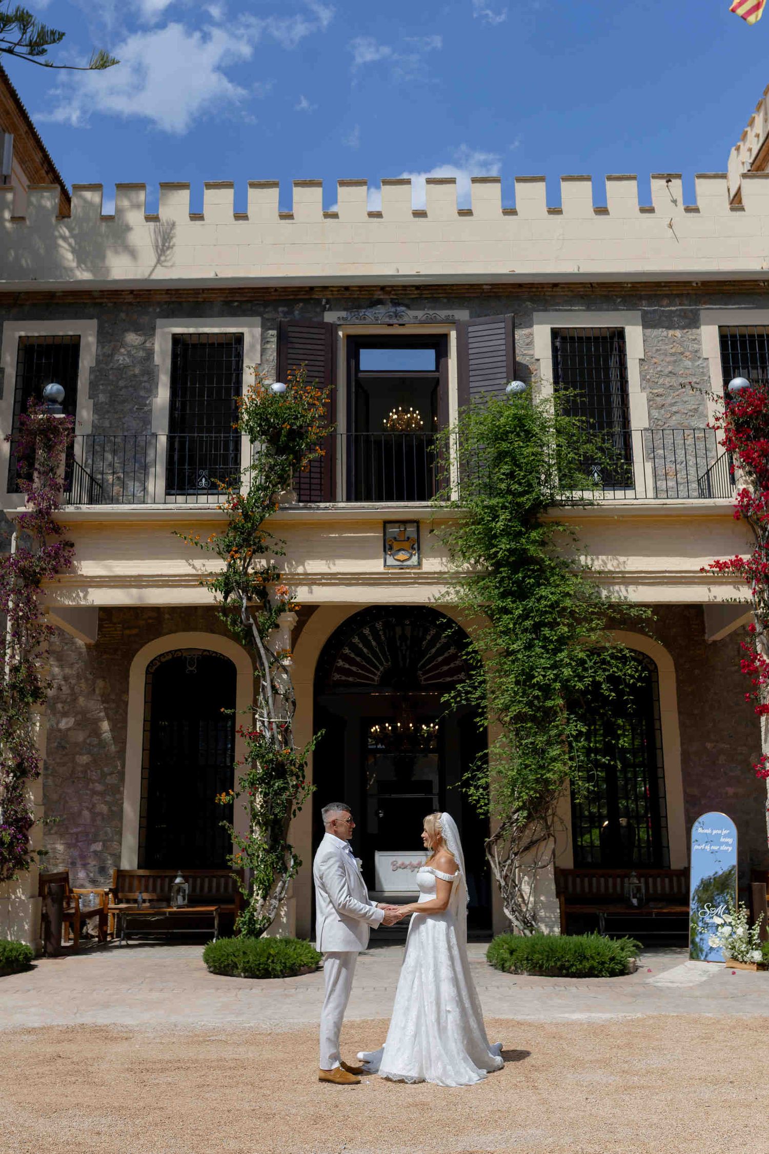 Bride and groom holding hands in front of a historic stone finca during a destination wedding in Altea.