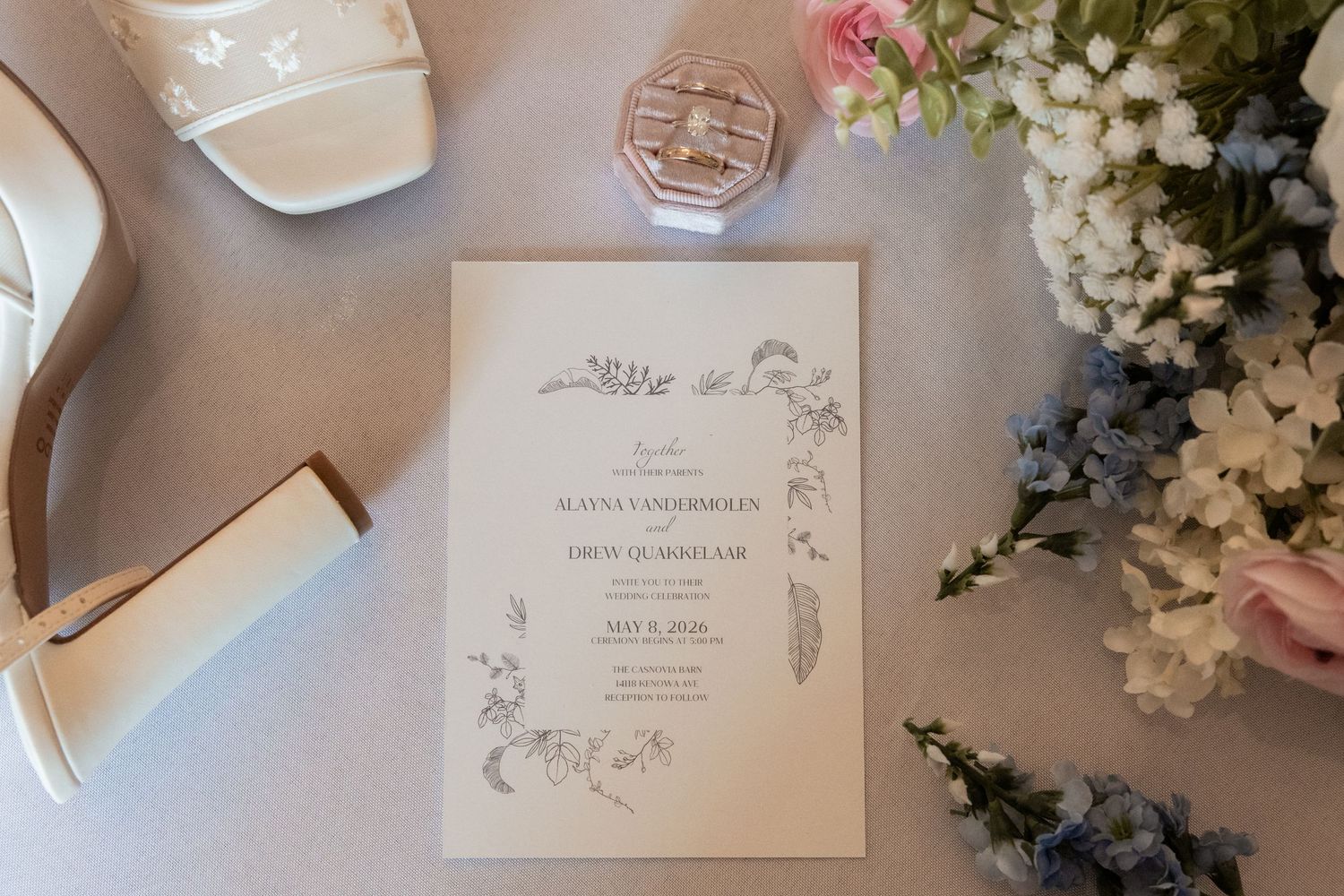 Elegant floral wedding invitation suite styled with bridal shoes, ring box, and fresh flowers.