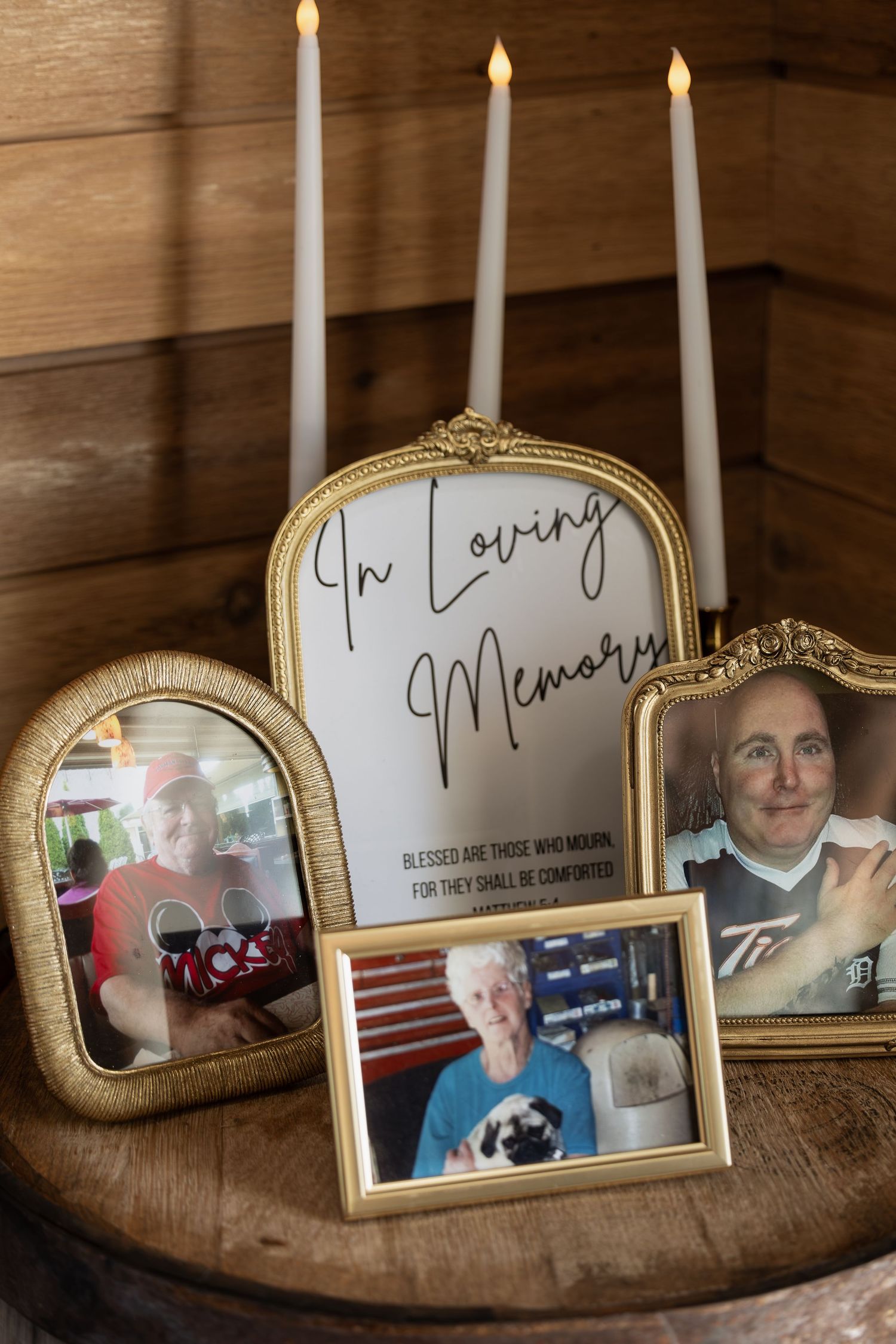 Gold-framed In Loving Memory memorial display with candles and family photos at a wedding reception.
