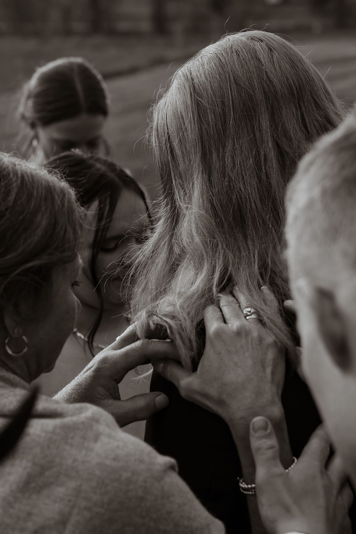 Black and white photo of emotional wedding moment with family members gathered in a close group embrace.