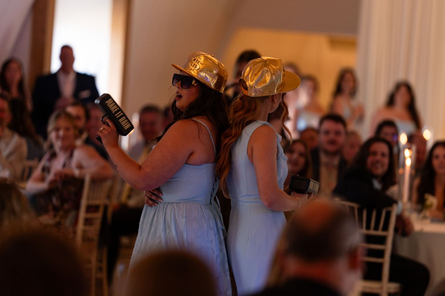 Bridesmaids in blue dresses wearing gold cowboy hats entertaining guests at wedding reception.