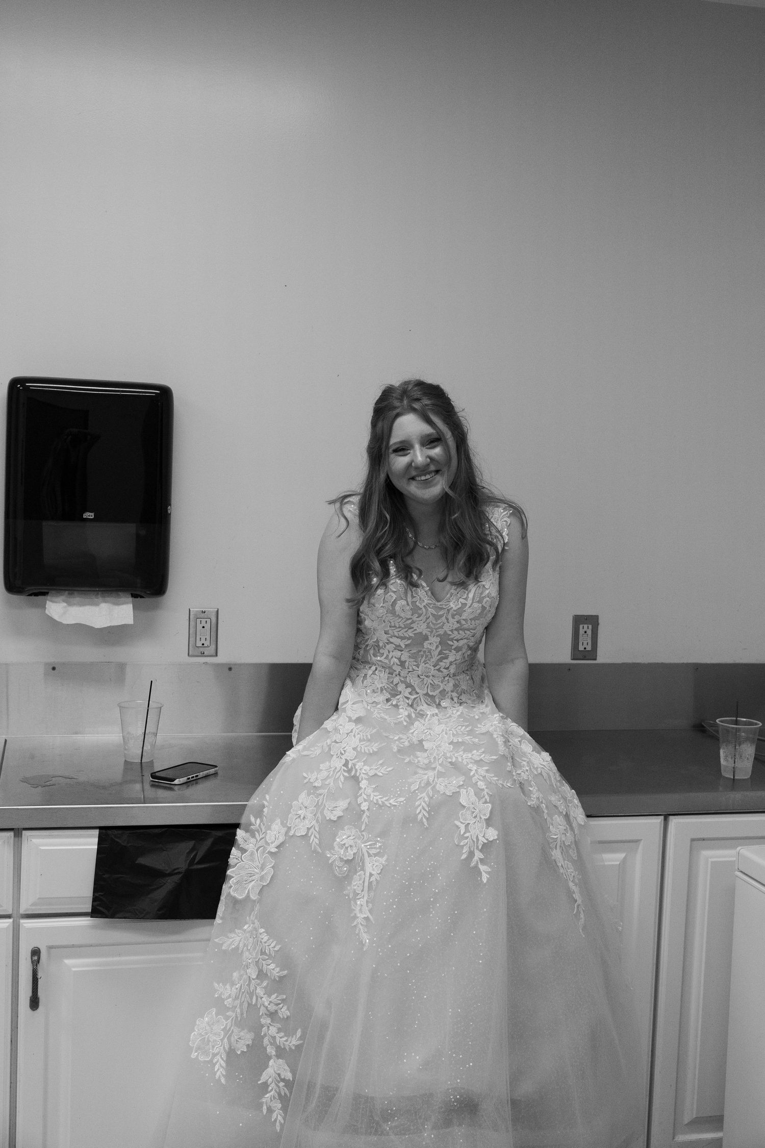 Smiling bride in lace ballgown wedding dress poses in black and white photo.
