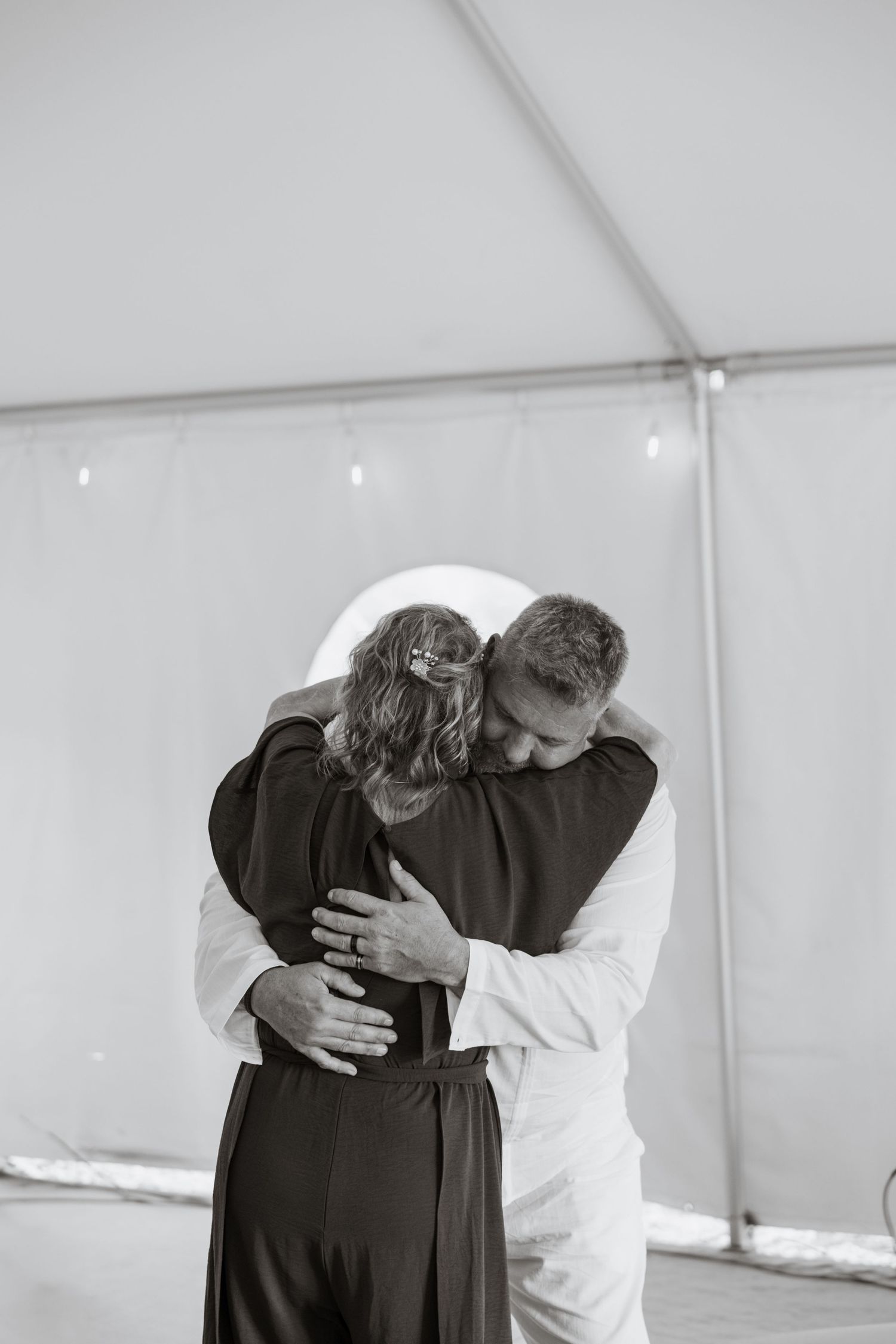 Emotional black and white photo of couple sharing tender hug during first dance at wedding.