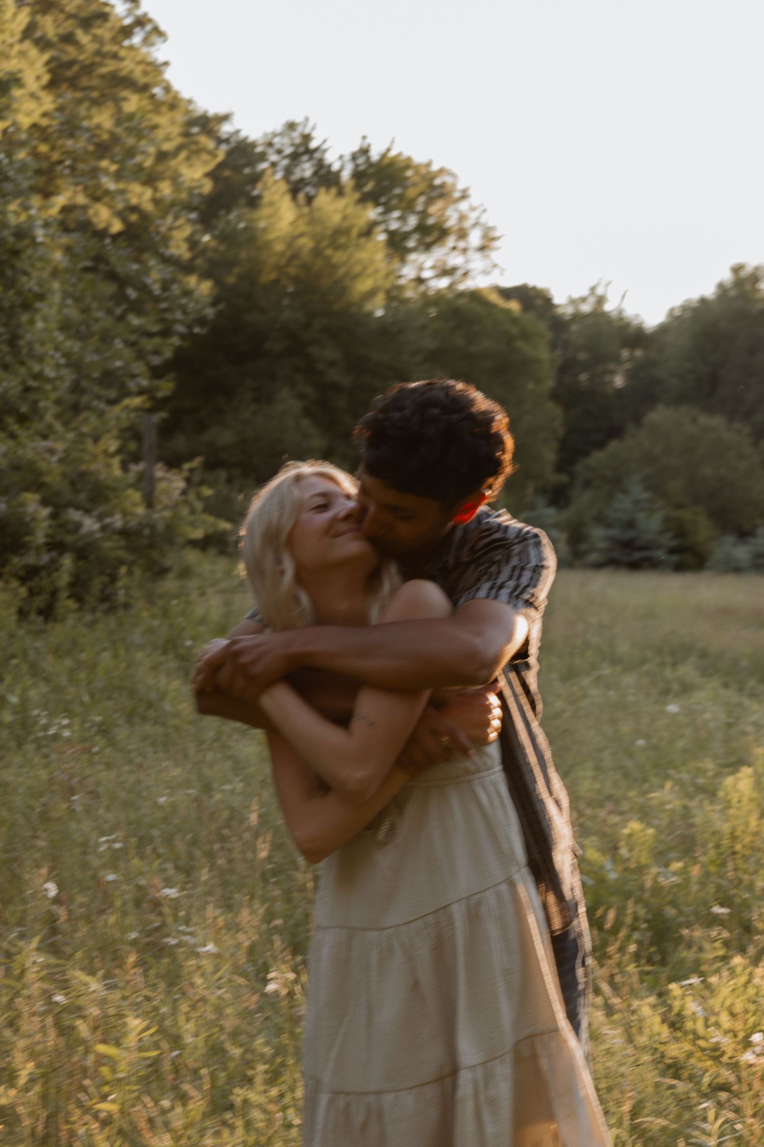 Romantic couple embracing and kissing in a golden hour green meadow.