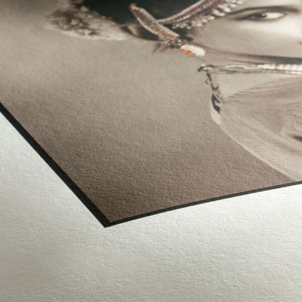 Corner detail of a fine art print on textured matte paper showing an Indian classical dancer portrait.