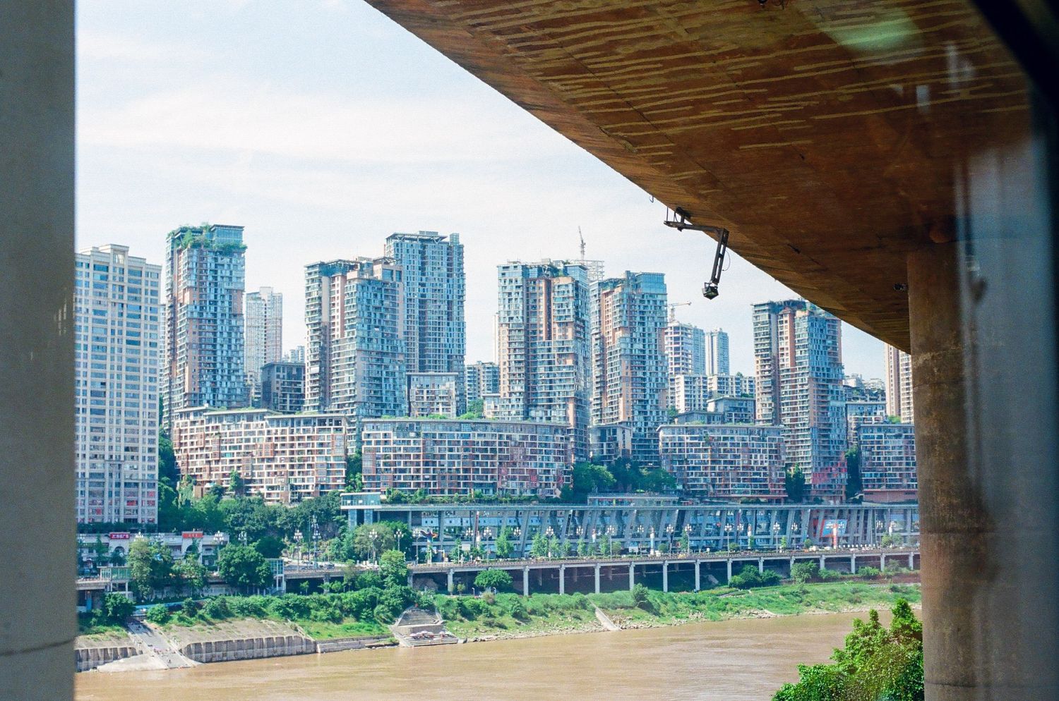 Aerial view of Chongqing skyline with high-rise buildings along the Yangtze River seen from under a bridge.