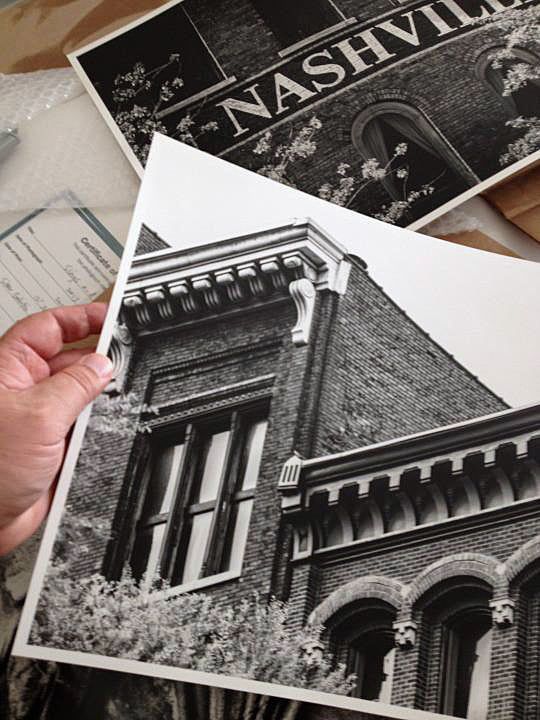 Hand holding a black and white photo print of a historic Nashville brick building with ornate architecture.