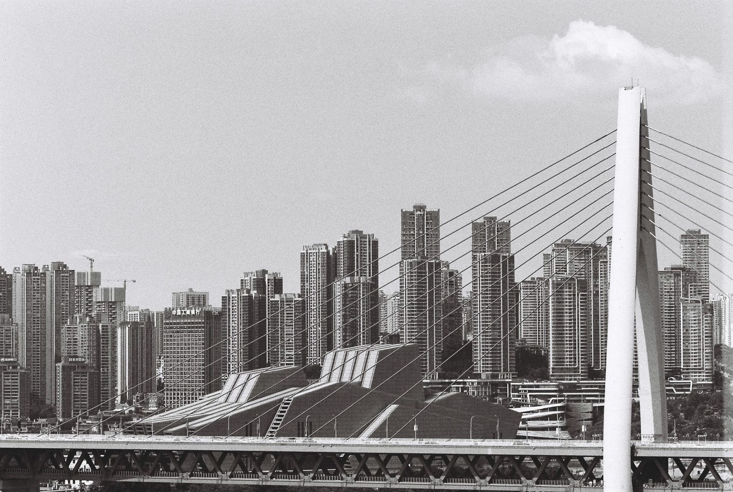 Black and white cityscape of Chongqing with cable-stayed bridge and skyscrapers.