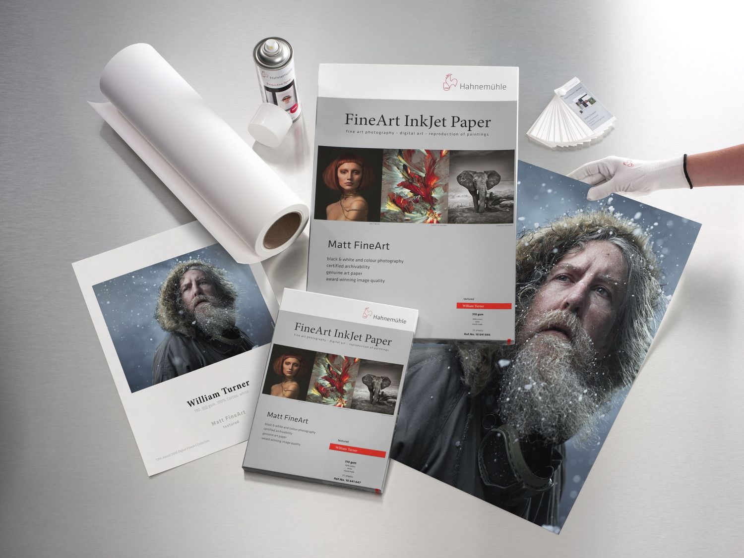 Hahnemuhle FineArt Inkjet Paper collection displayed with printed portrait photographs and paper rolls.