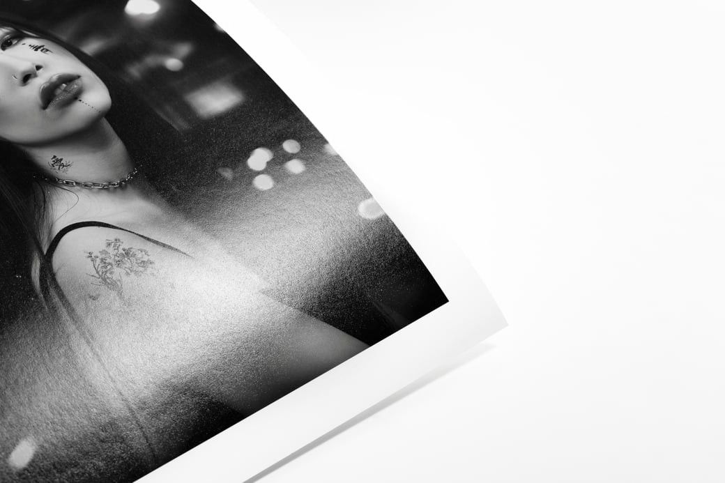 Black and white fine art print of a tattooed woman with bokeh lights in the background.