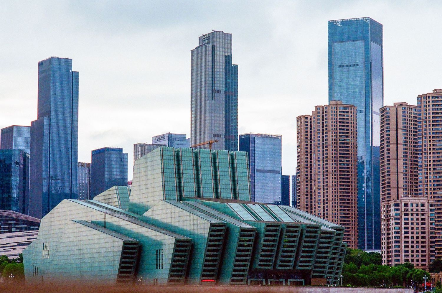 Chongqing, modern city skyline featuring a distinctive angular green building amid towering skyscrapers.