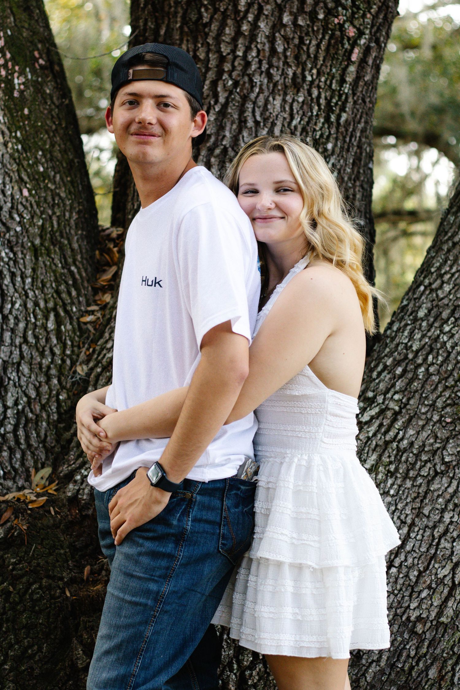 Couple standing together as the woman hugs the man from behind during an outdoor photography session