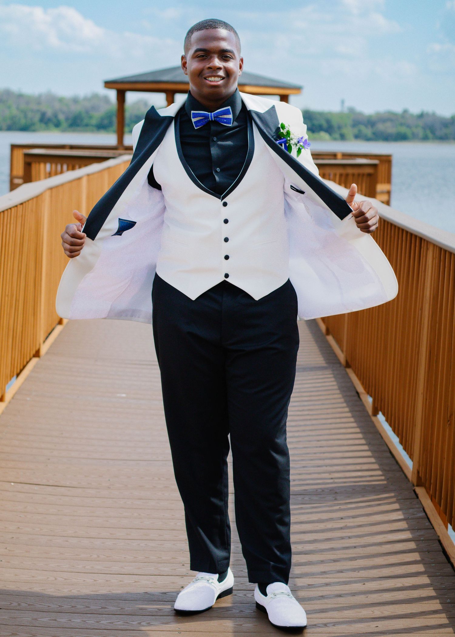 High school senior boy posing for prom photos with his jacket flared during an outdoor photography session