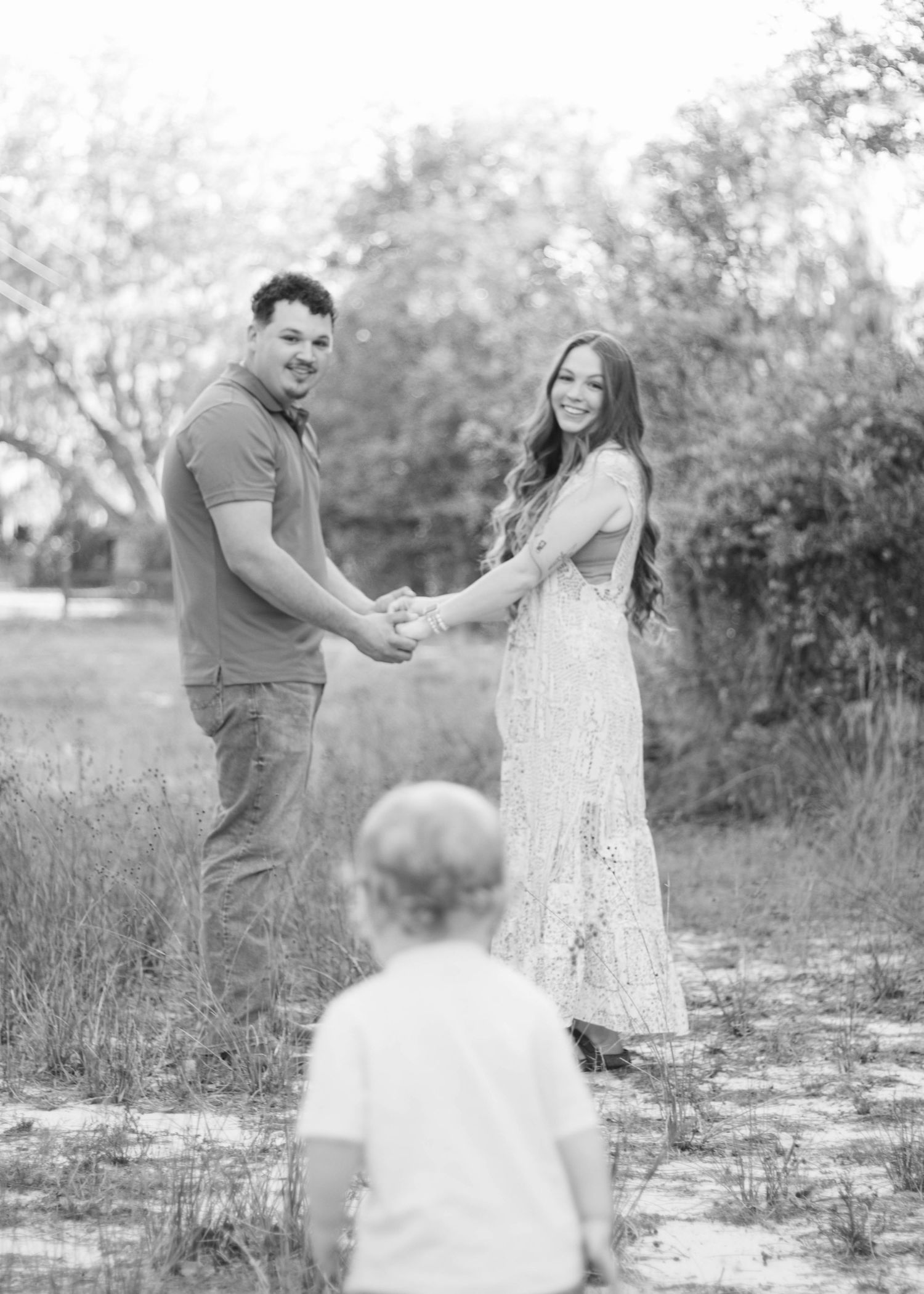 Parents watching their son walk toward them during an outdoor family photography session