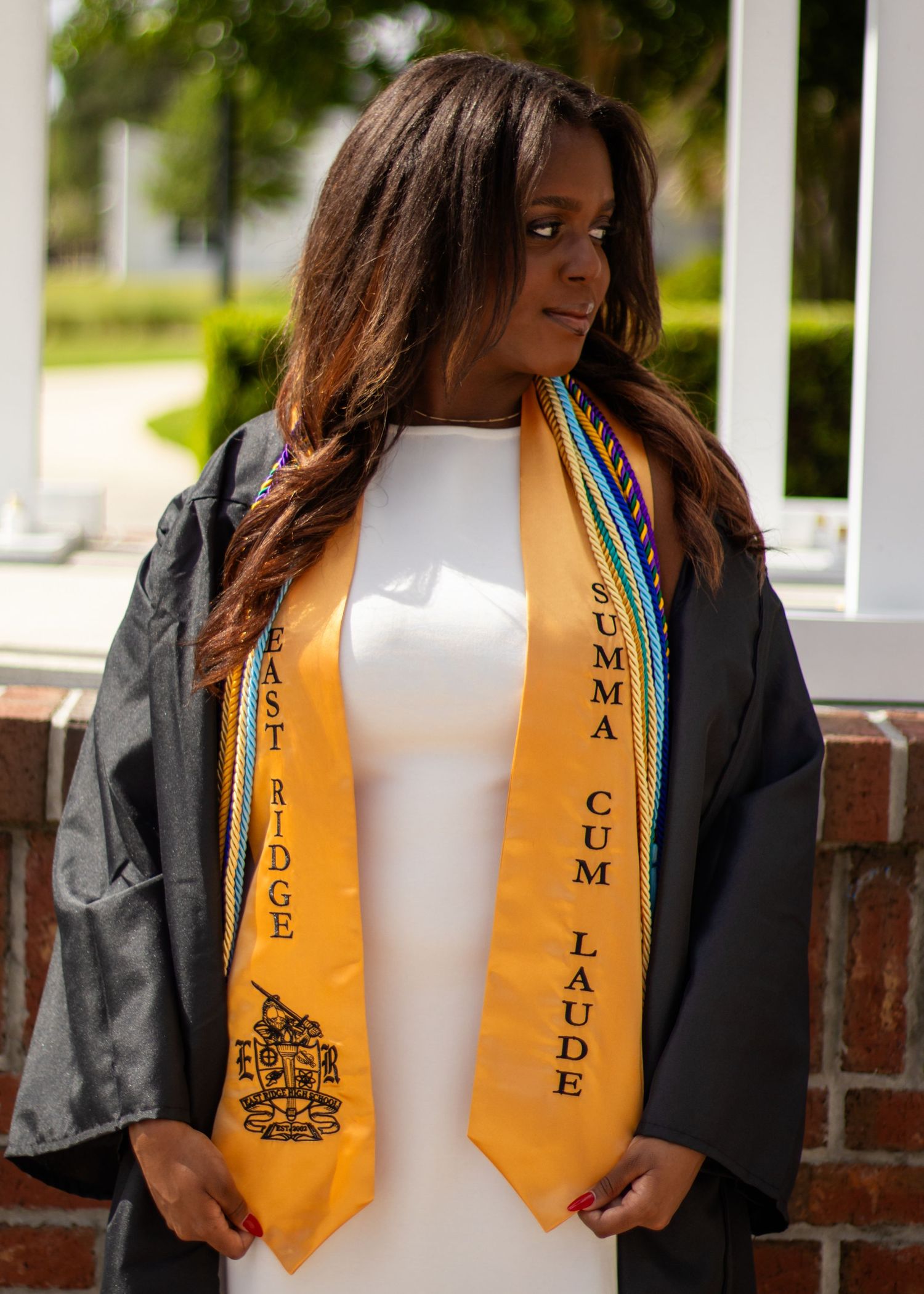 High school senior girl posing with her graduation regalia during an outdoor senior photography session