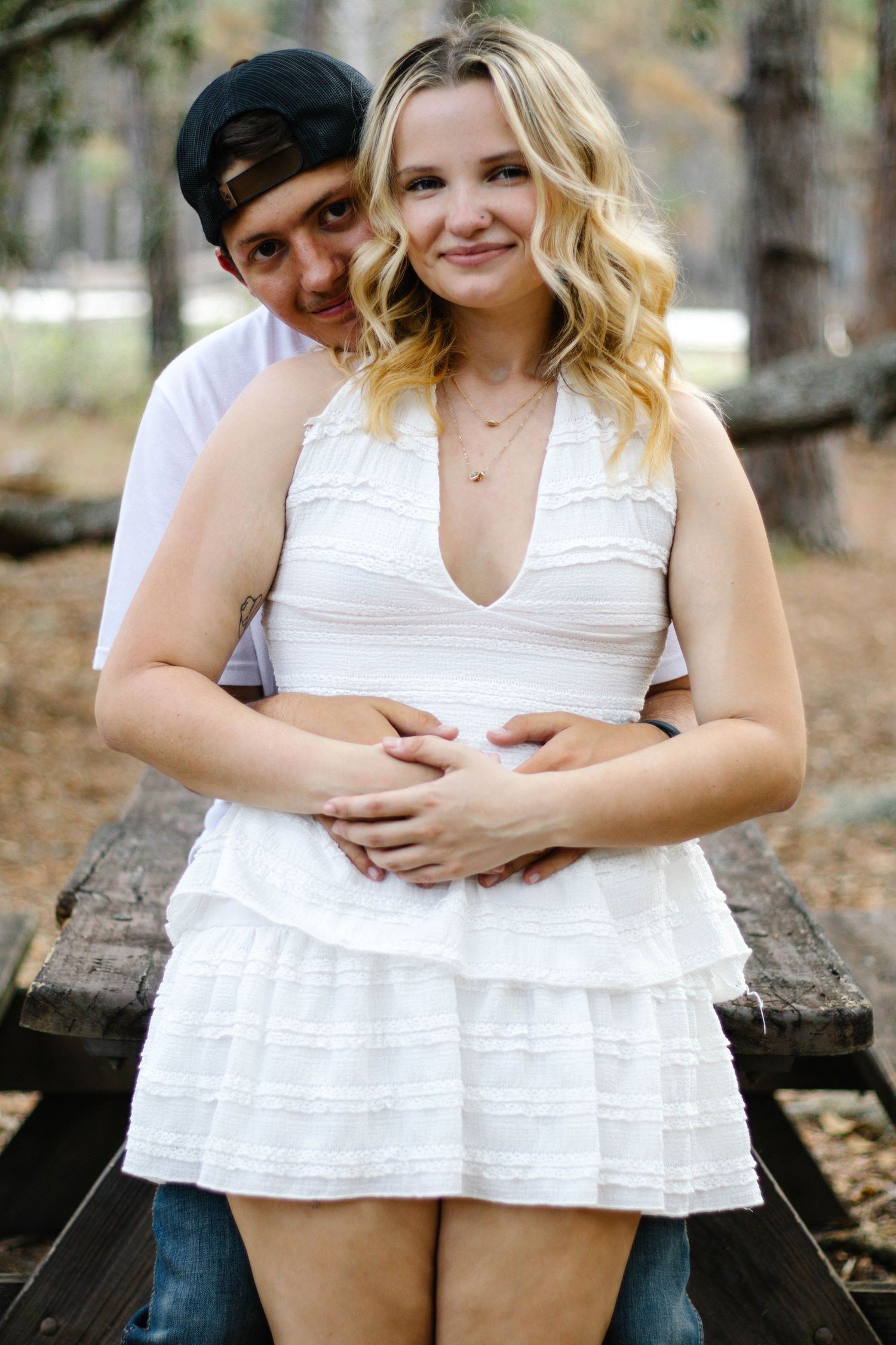 Couple leaning against a bench as the man hugs the woman from behind during an outdoor photography session