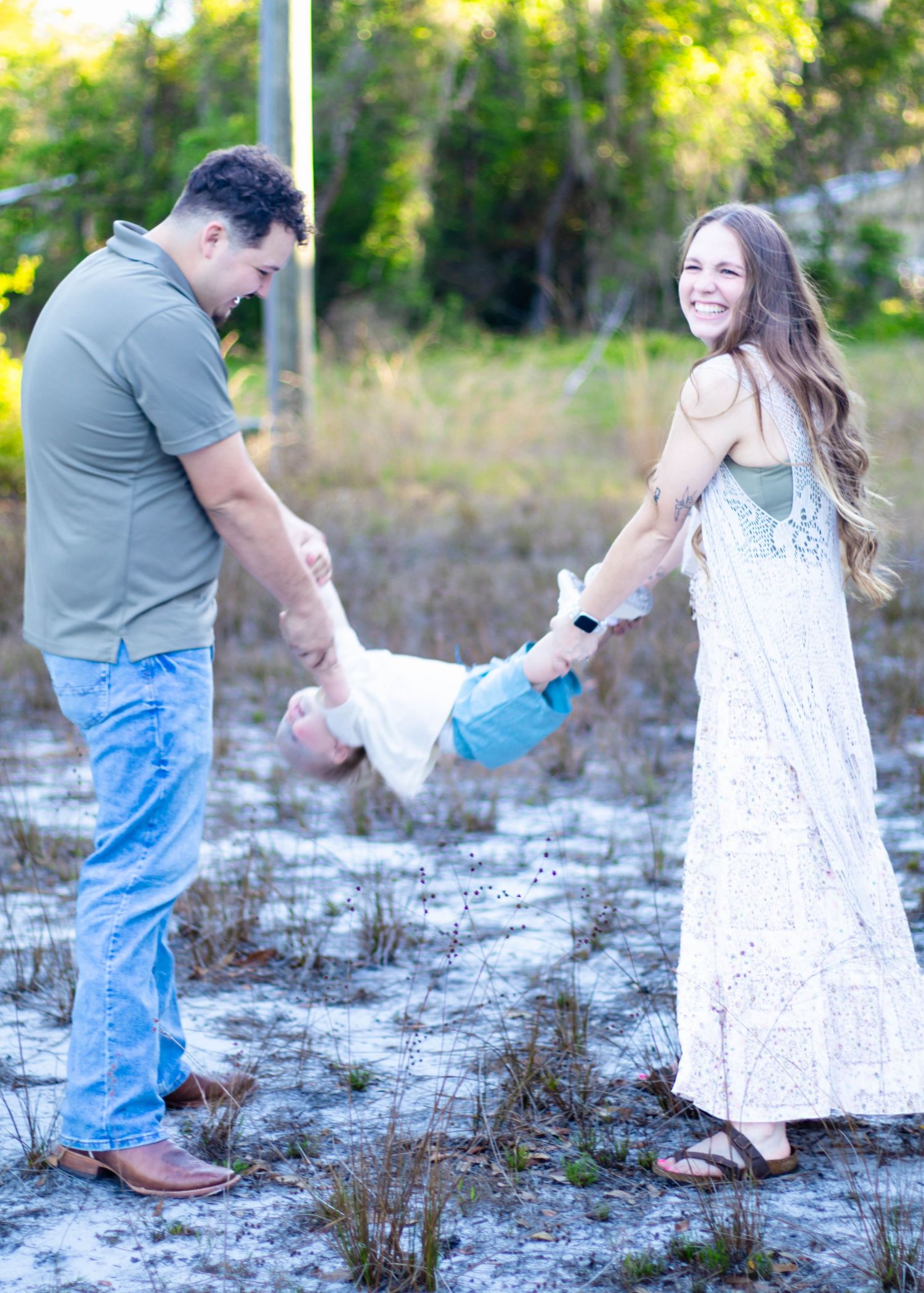 Parents swinging their child between them while laughing during an outdoor family photography session