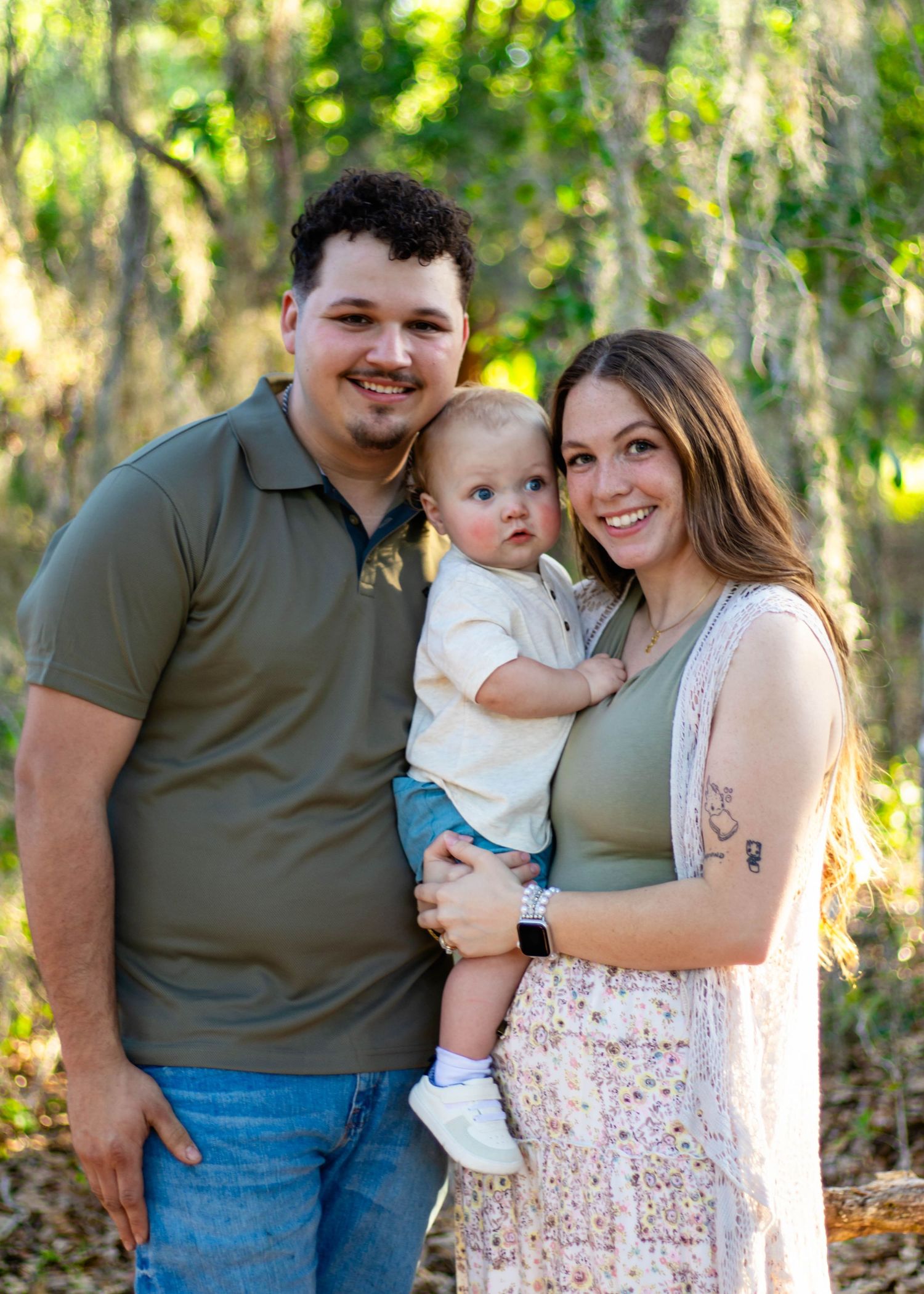 Family posing together outdoors with moss-covered trees in the background