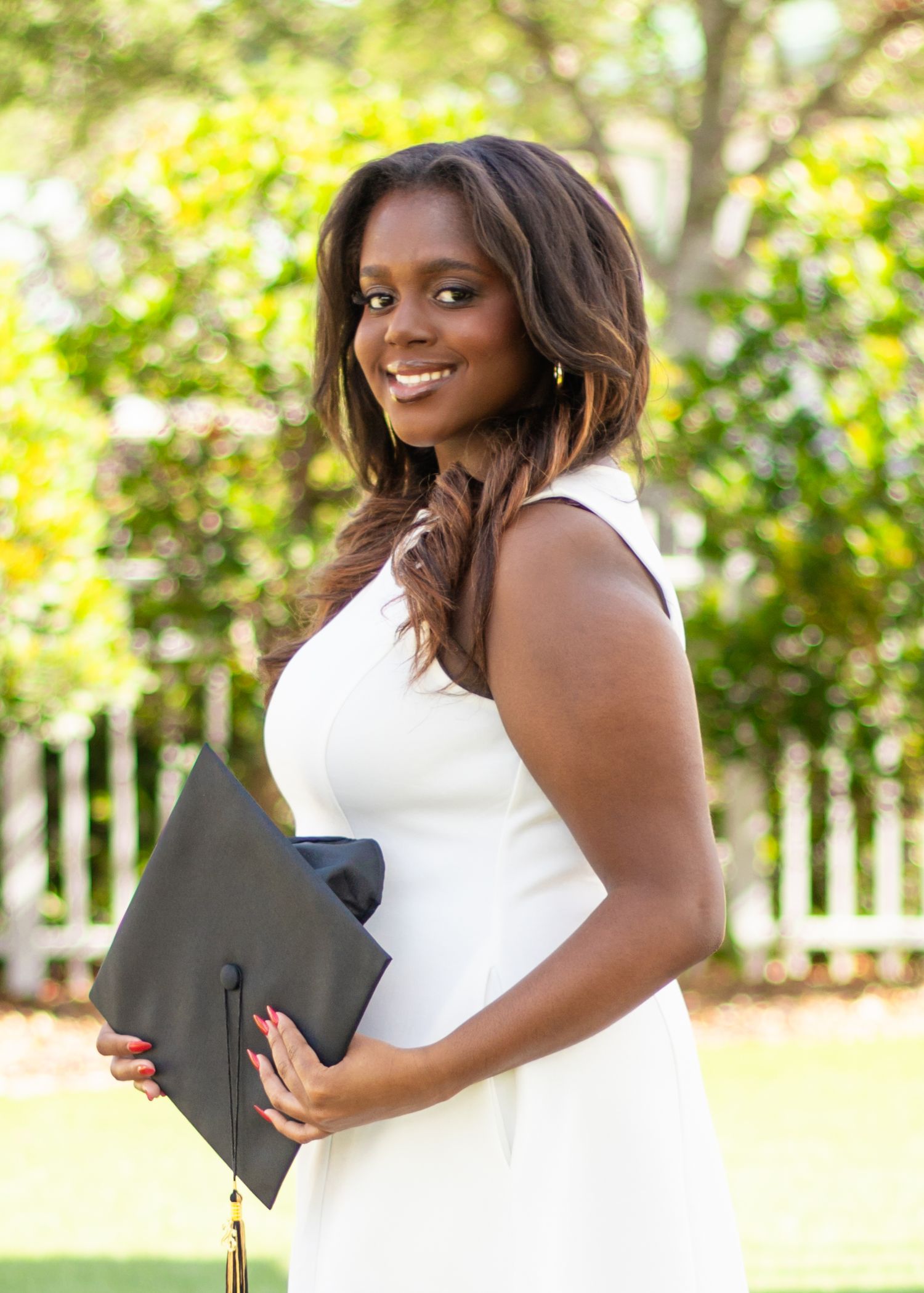 High school senior girl standing outdoors holding her graduation cap during a senior photography session