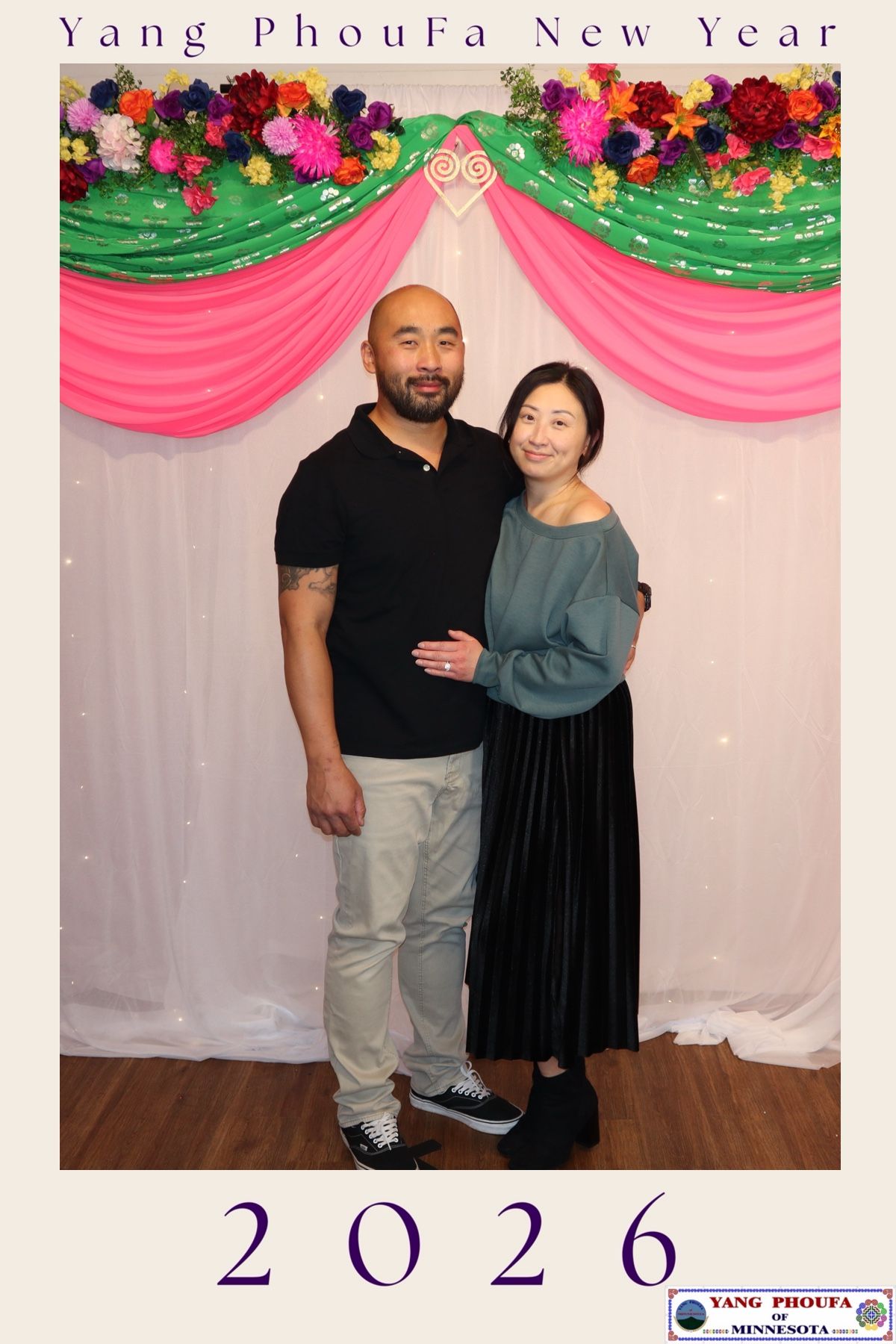 Man and woman posing together at Yang PhouFa New Year 2026 celebration before decorated backdrop.