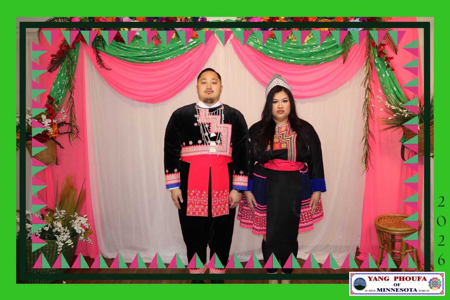 Couple in traditional Hmong black and red outfits poses at a Yang Phoua Minnesota photo booth.