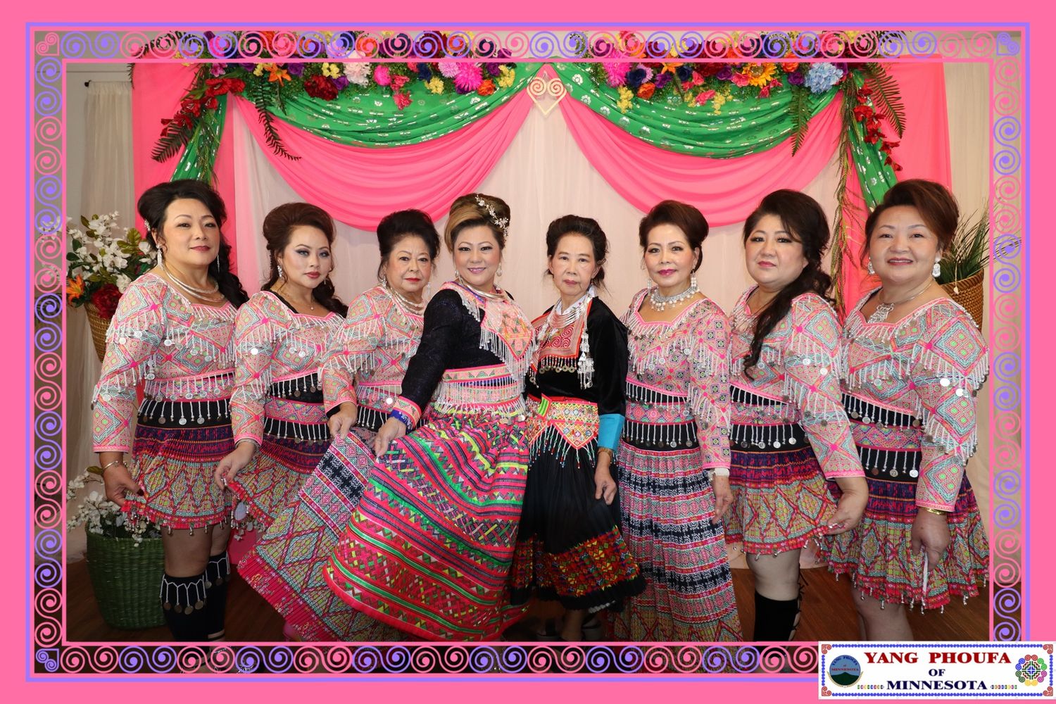 Group of women in traditional Hmong attire posing together at a festive celebration in Minnesota.