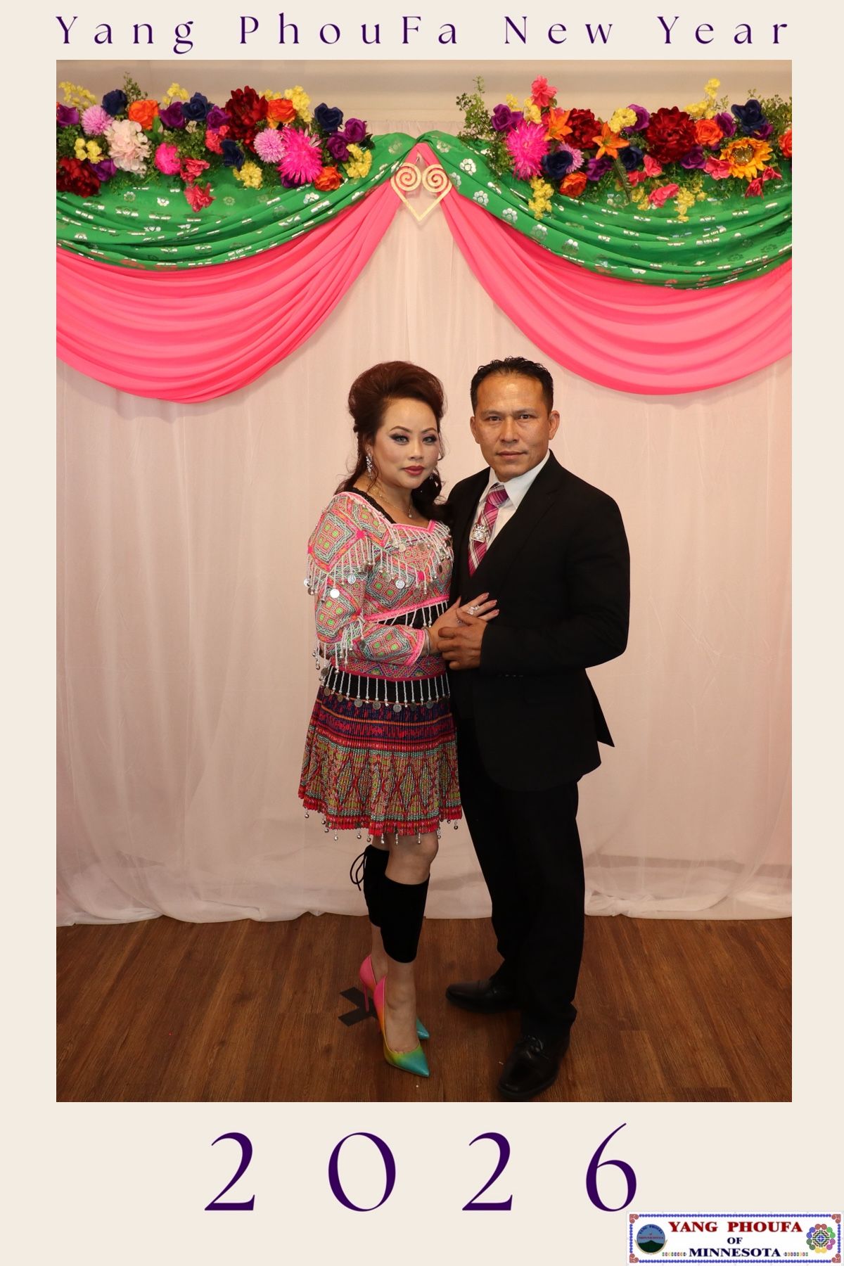 Couple posing at Yang PhouFa New Year 2026 celebration in Minnesota, woman in traditional Hmong dress, man in black suit.