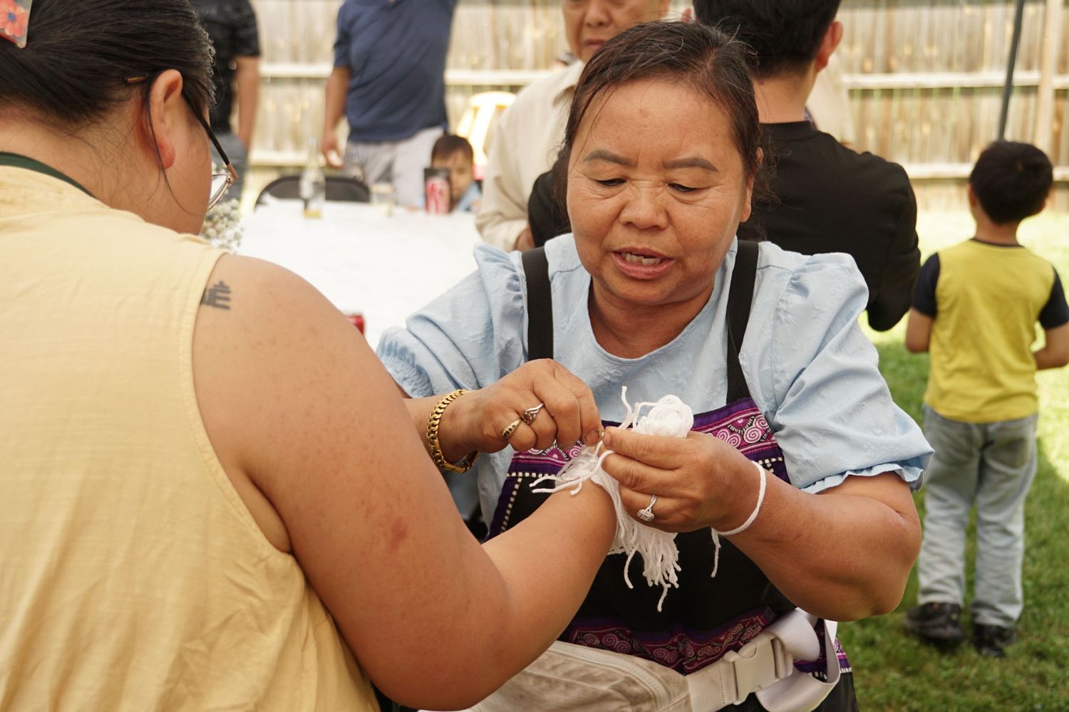 Two women engage in a traditional craft activity at an outdoor cultural festival event.