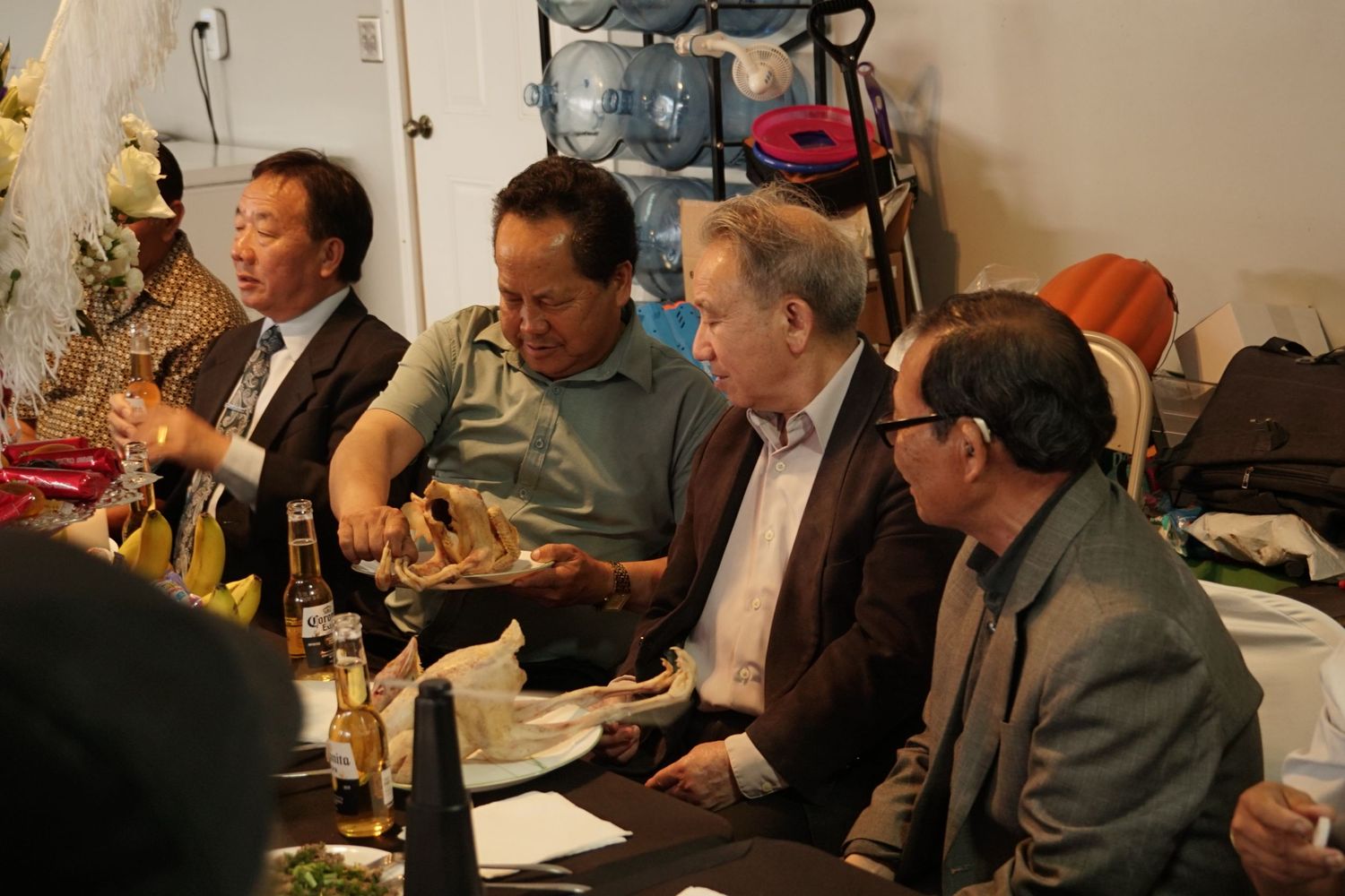 Four men gathered around a table at an indoor dinner party, sharing food and conversation in a casual setting.
