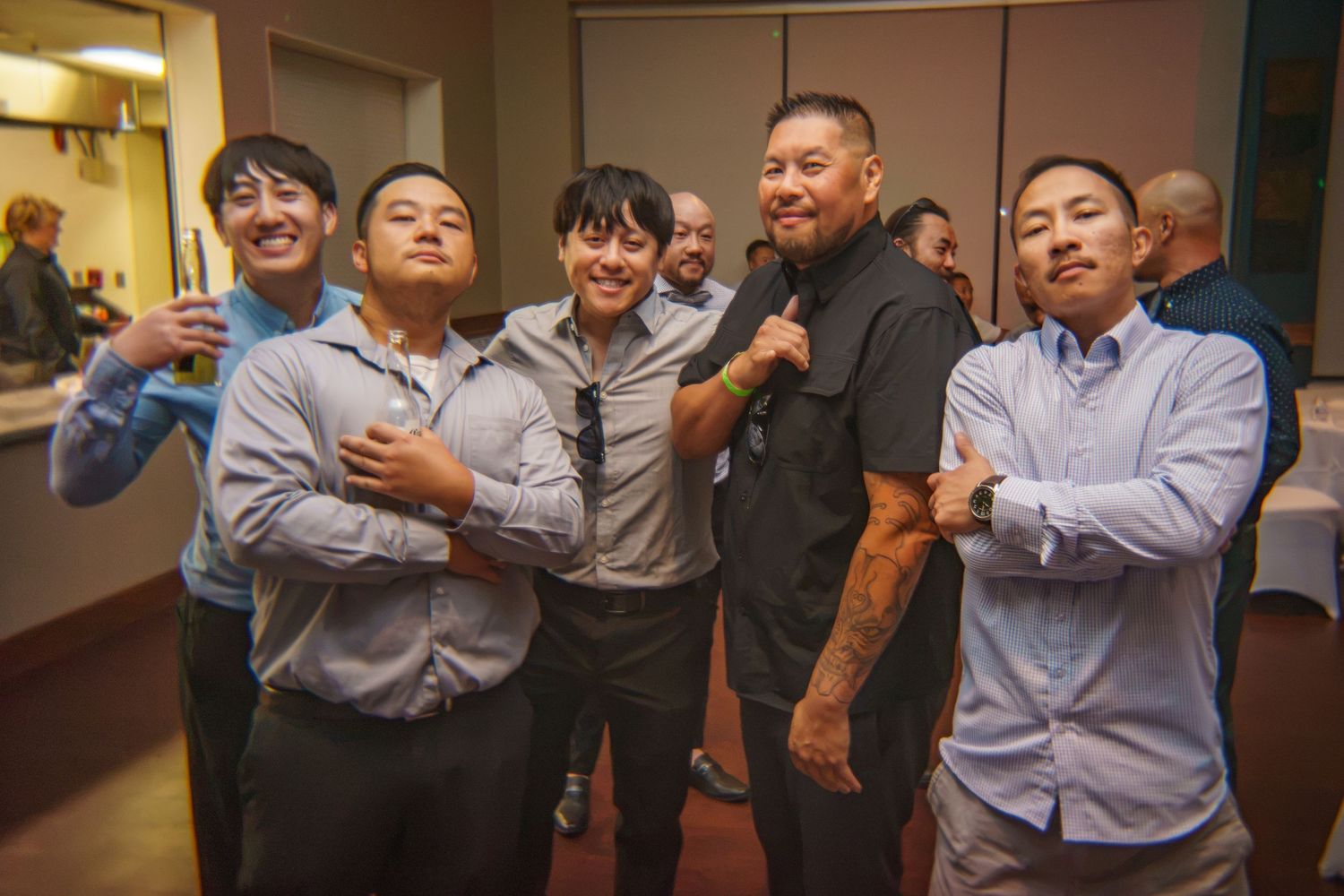 Group of five young men posing and smiling together at an indoor social gathering or celebration event.