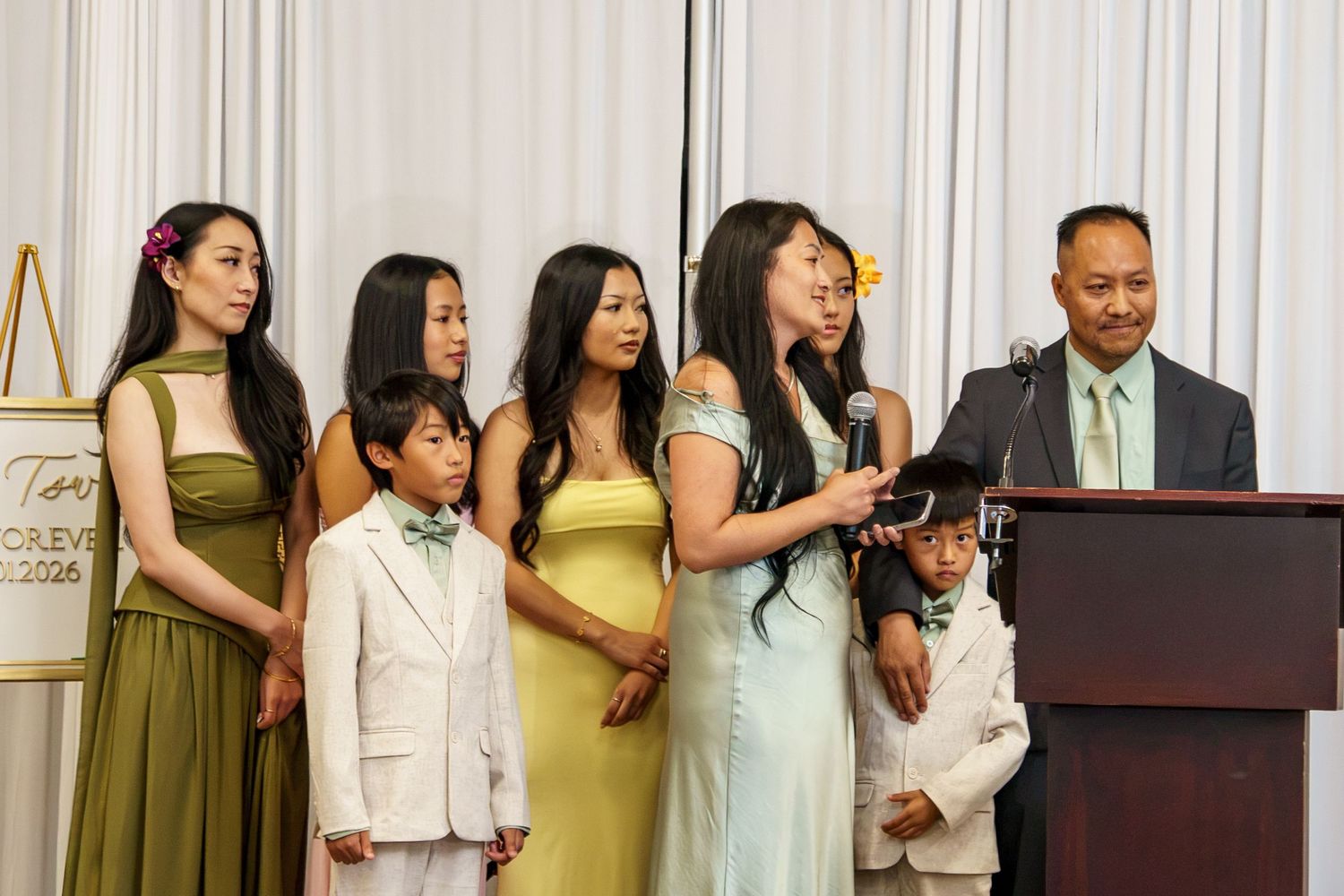 Family group in formal attire stands at podium during elegant event ceremony.