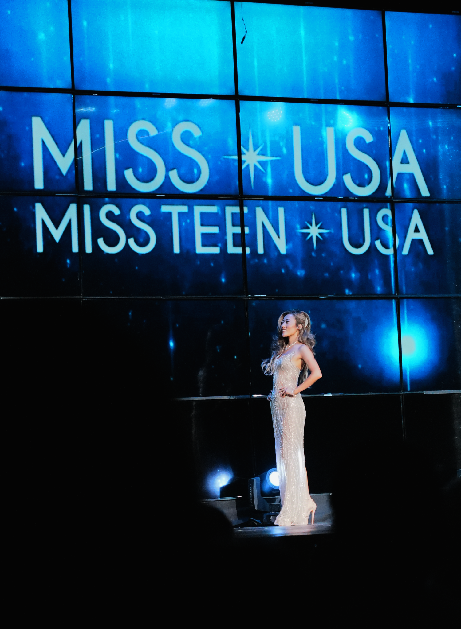 A contestant in a white gown performs on stage at the Miss USA and Miss Teen USA pageant competition.