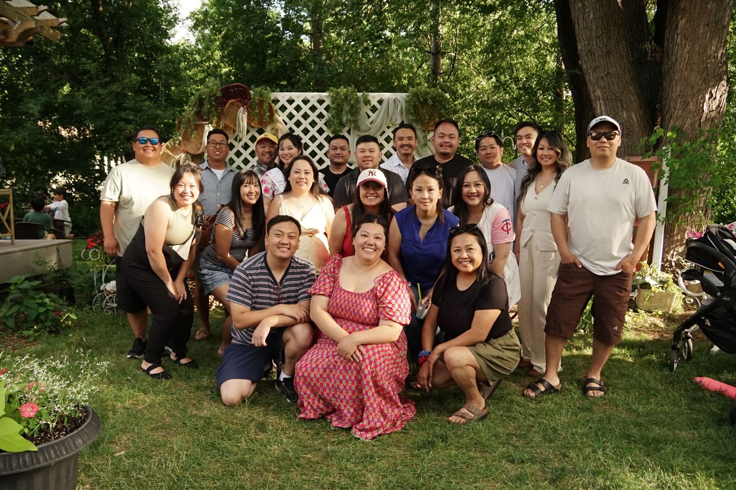 Large family group posing outdoors in a lush garden during a sunny summer gathering.