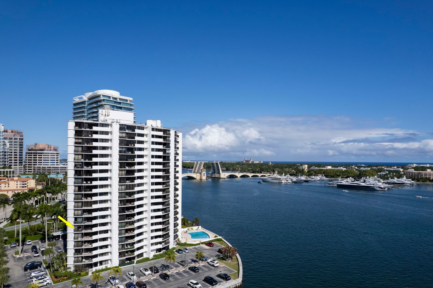 Luxury waterfront high-rise condo tower overlooking a marina and bridge in West Palm Beach, Florida. Palm Beach Real Estate aerial views by