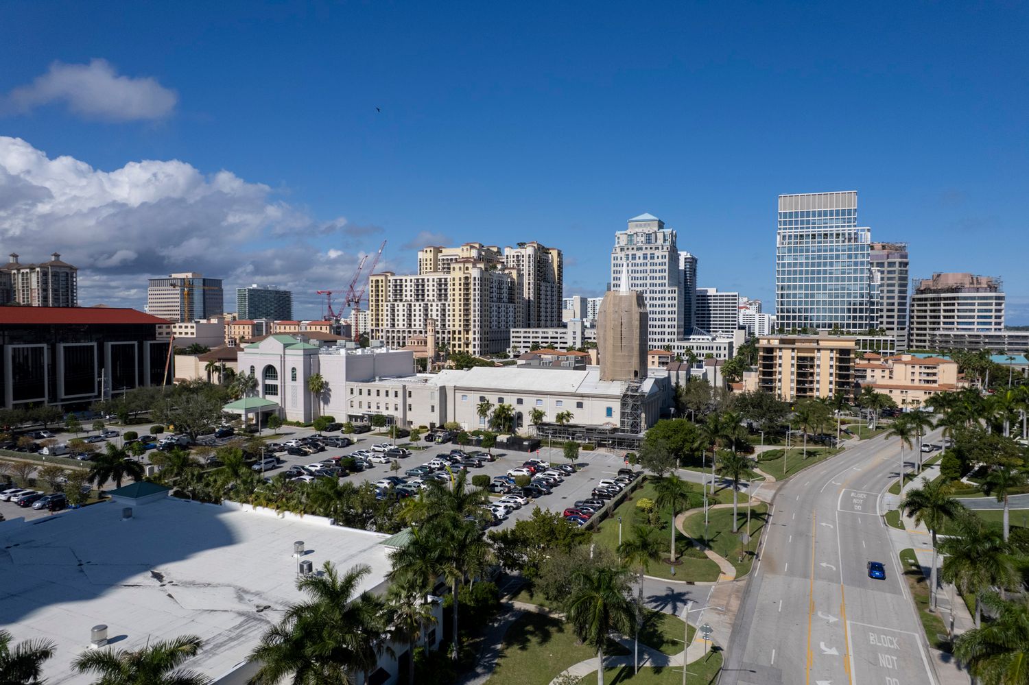 Palm Beach Real Estate aerial views of downtown West Palm Beach skyline with palm trees, parking lots, and wide roads.